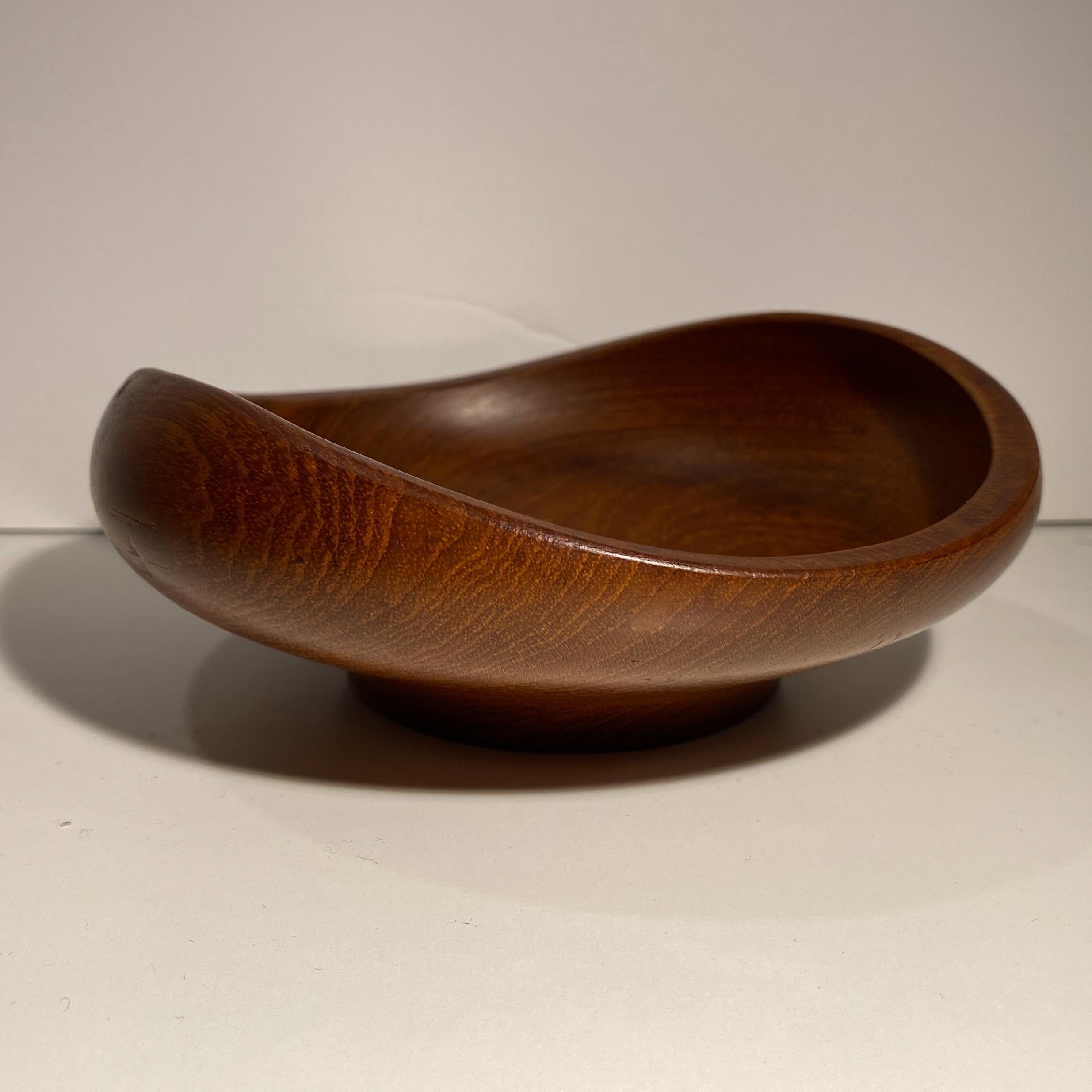 Footed teak bowl with a swooping curvilinear shape. Designed by Finn Juhl for Kay Bojesen and produced in Denmark, circa 1950s. The bowl has been cleaned and polished but retains its original finish with a deep, uniform patina. Etched signature