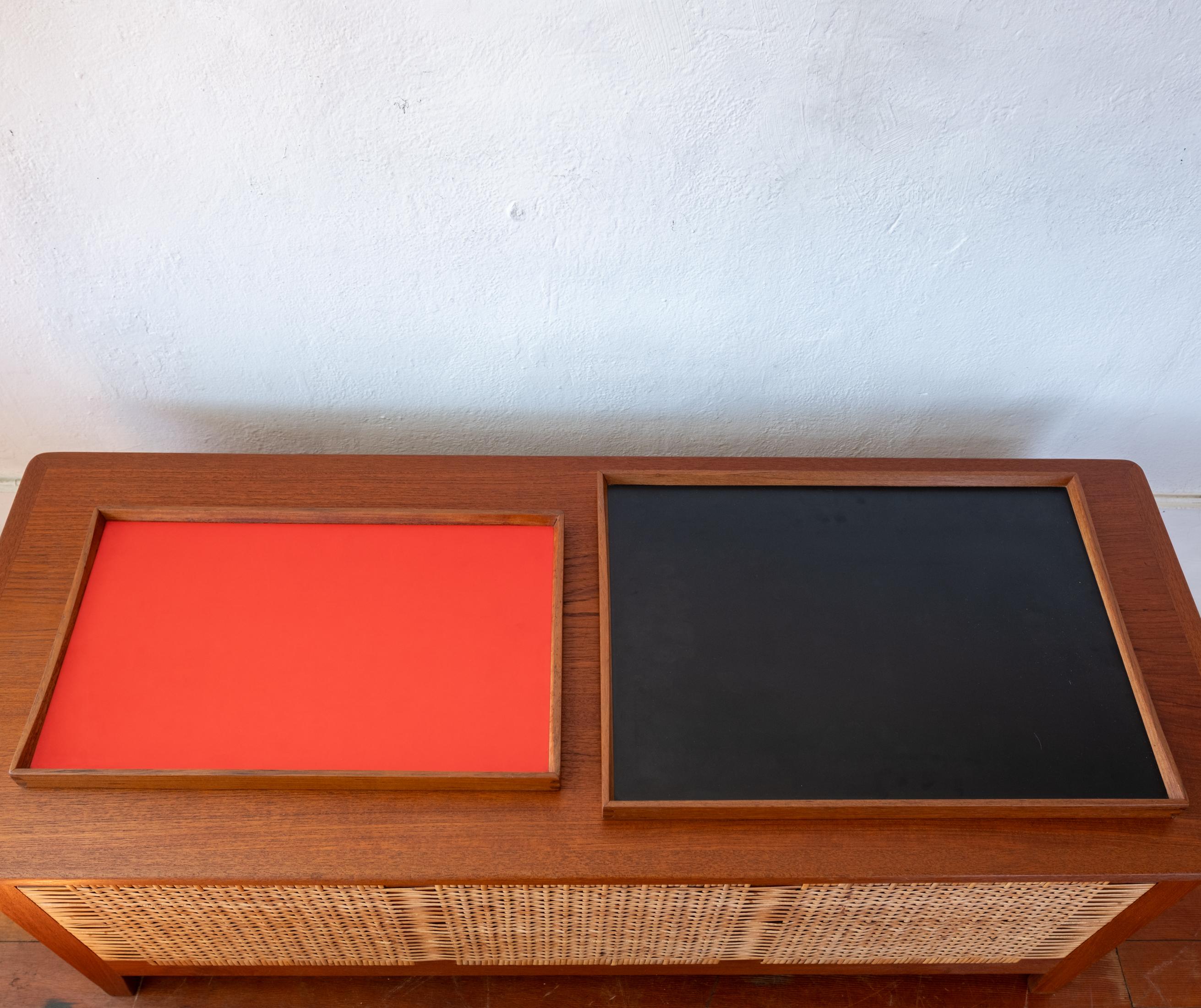Dos bandejas de doble cara para escritorio o bar diseñadas por Finn Juhl y fabricadas por el ebanista Torben Orskov a partir de la. La bandeja más grande conserva la etiqueta original. Pareja nido reversible roja y negra. Barandillas de teca maciza