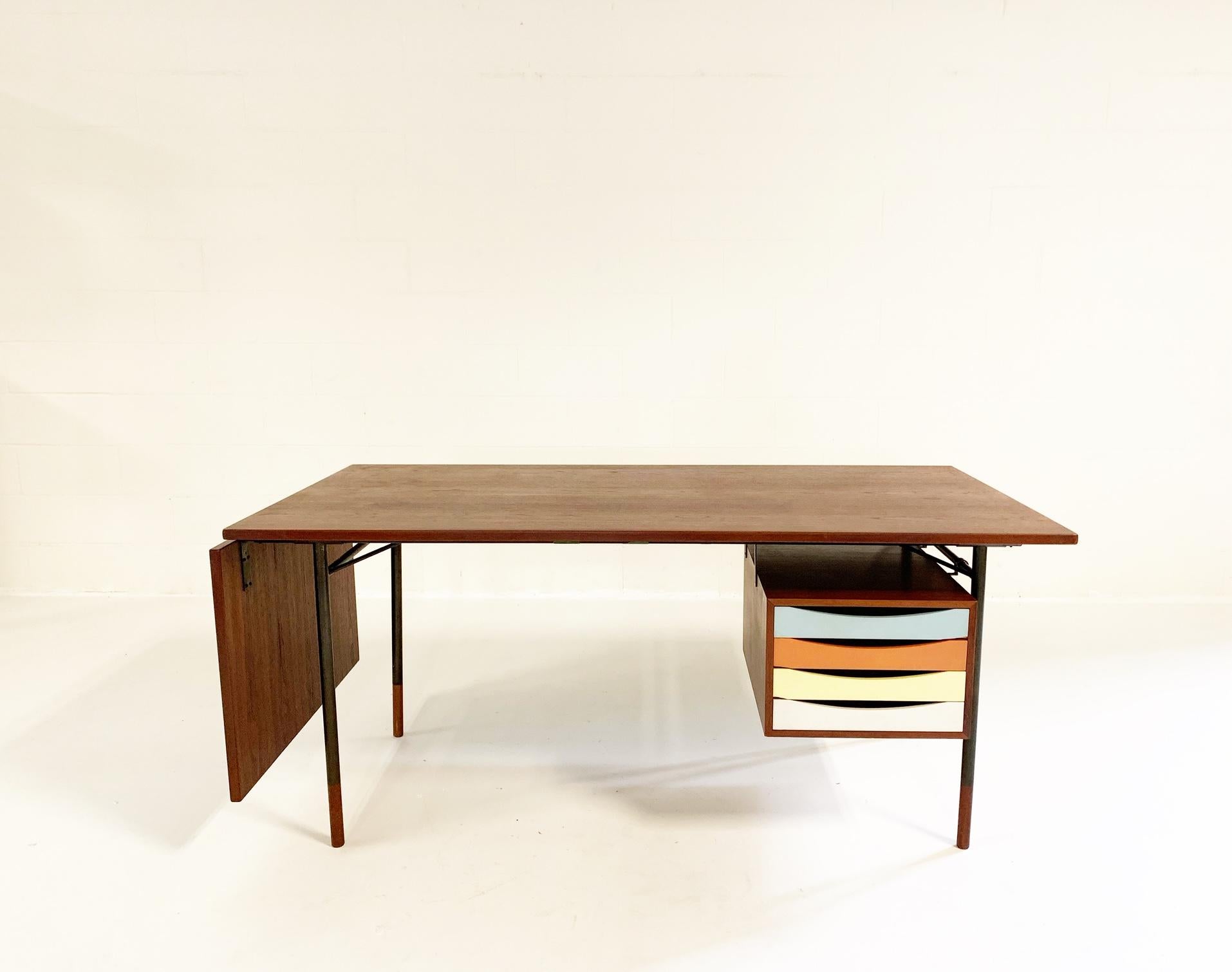 This a wonderful example of a Finn Juhl freestanding teak writing desk with detachable 20.25 inch flip-down leaf, the table measures 88.25 inches when fully extended. The drawer section has four polychrome lacquered drawers. The desk features an