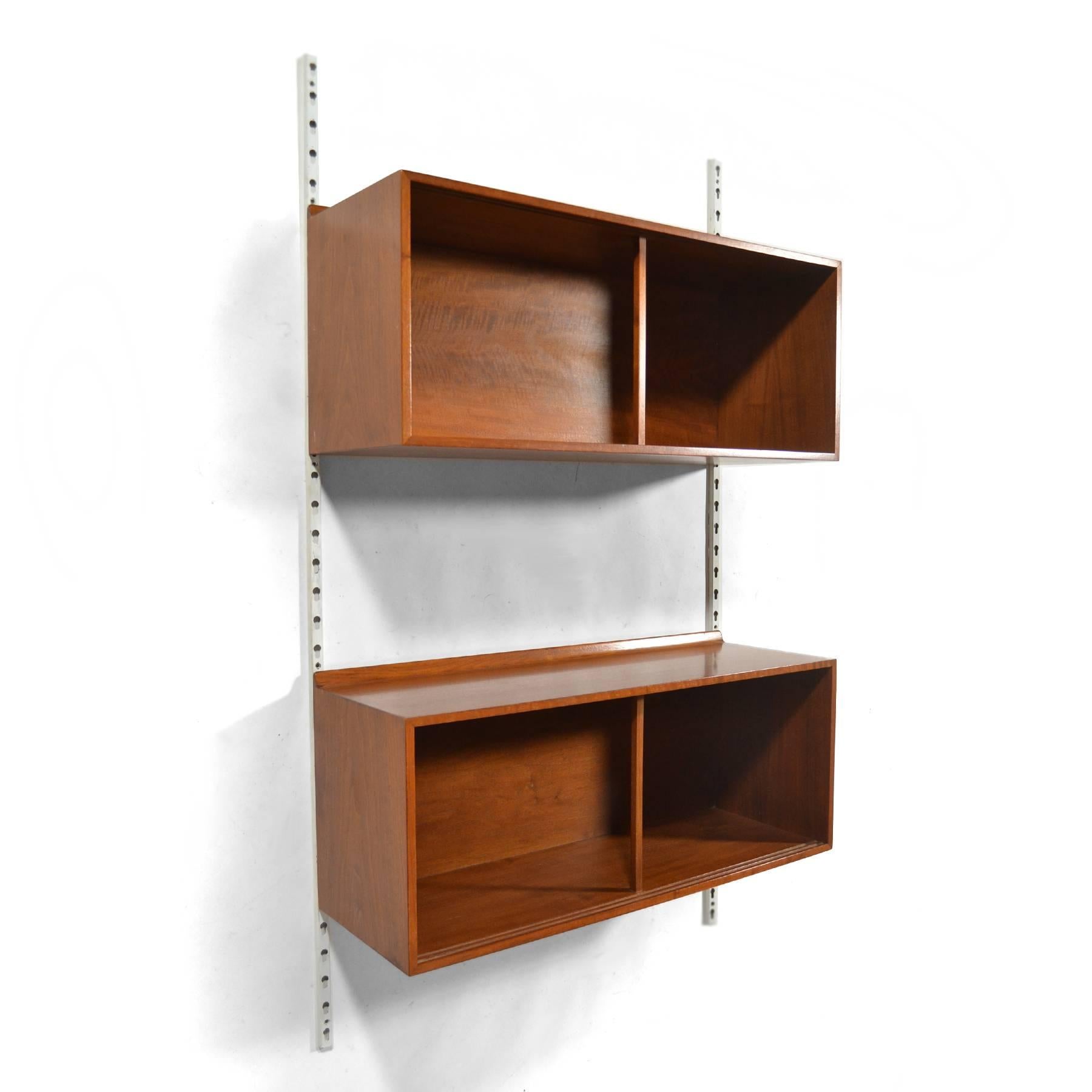 This pair of walnut Finn Juhl wall-mounted cases mount on metal uprights and can be adjusted and configured as desired. They feature details that many of Juhl's designs for Baker Furniture share, including the raised lip on the back edge.