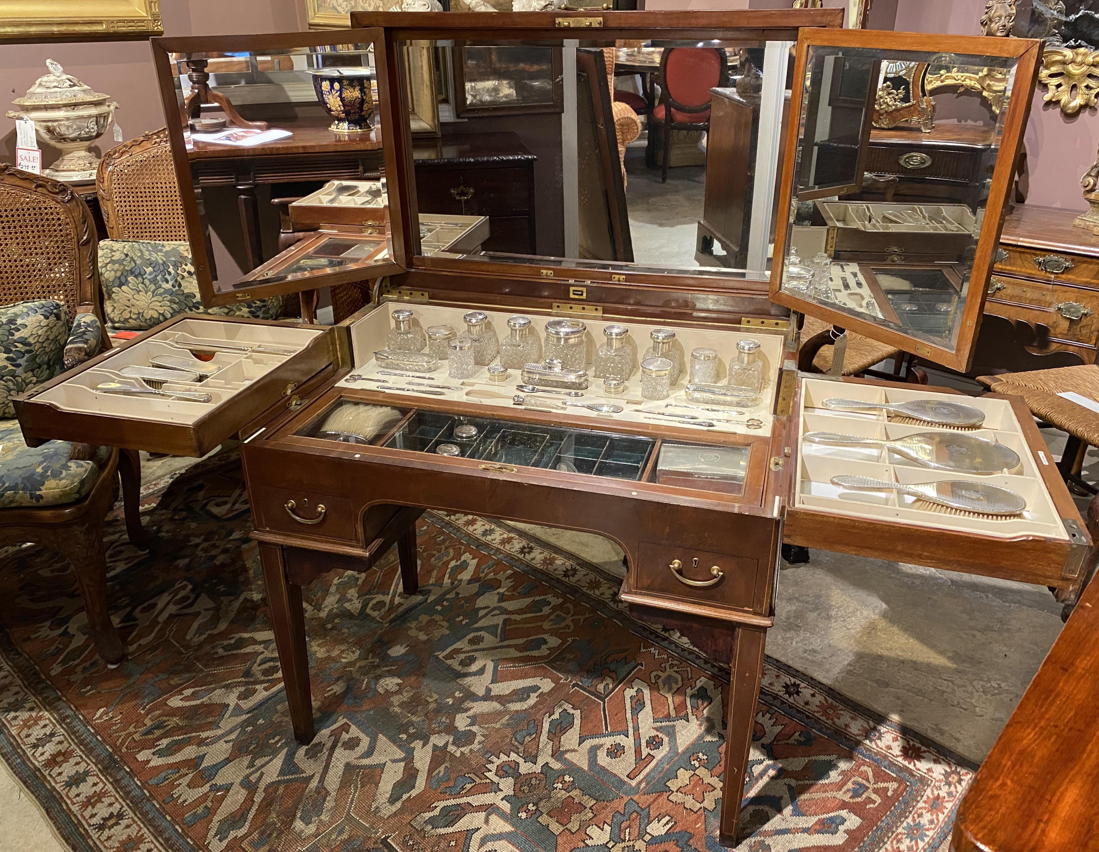 Un ottimo esempio di squisita toeletta Finnegan's of London in mogano massiccio e impiallacciato di mogano. Il tavolo pieghevole supporta uno schienale a tre specchi e lati pieghevoli. Si apre per rivelare circa 40 barattoli e spazzole di metallo,