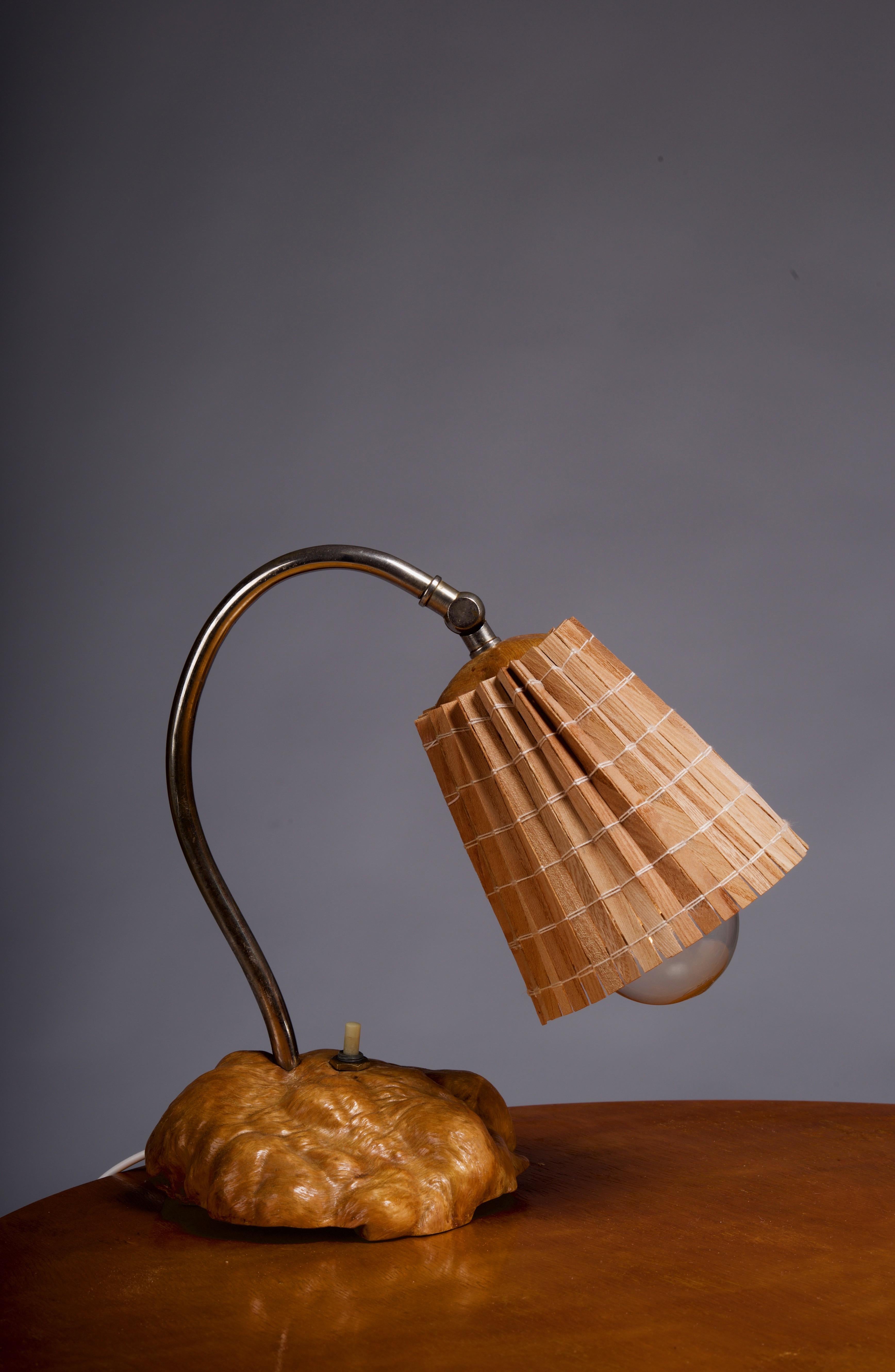 Illuminate your space with the organic beauty of the Finnish 1930/40's burl wood table lamp. This unique, hand-made treasure features a stunning wooden slat shade, casting a warm, soft light that adds a touch of Scandinavian charm to any room. This
