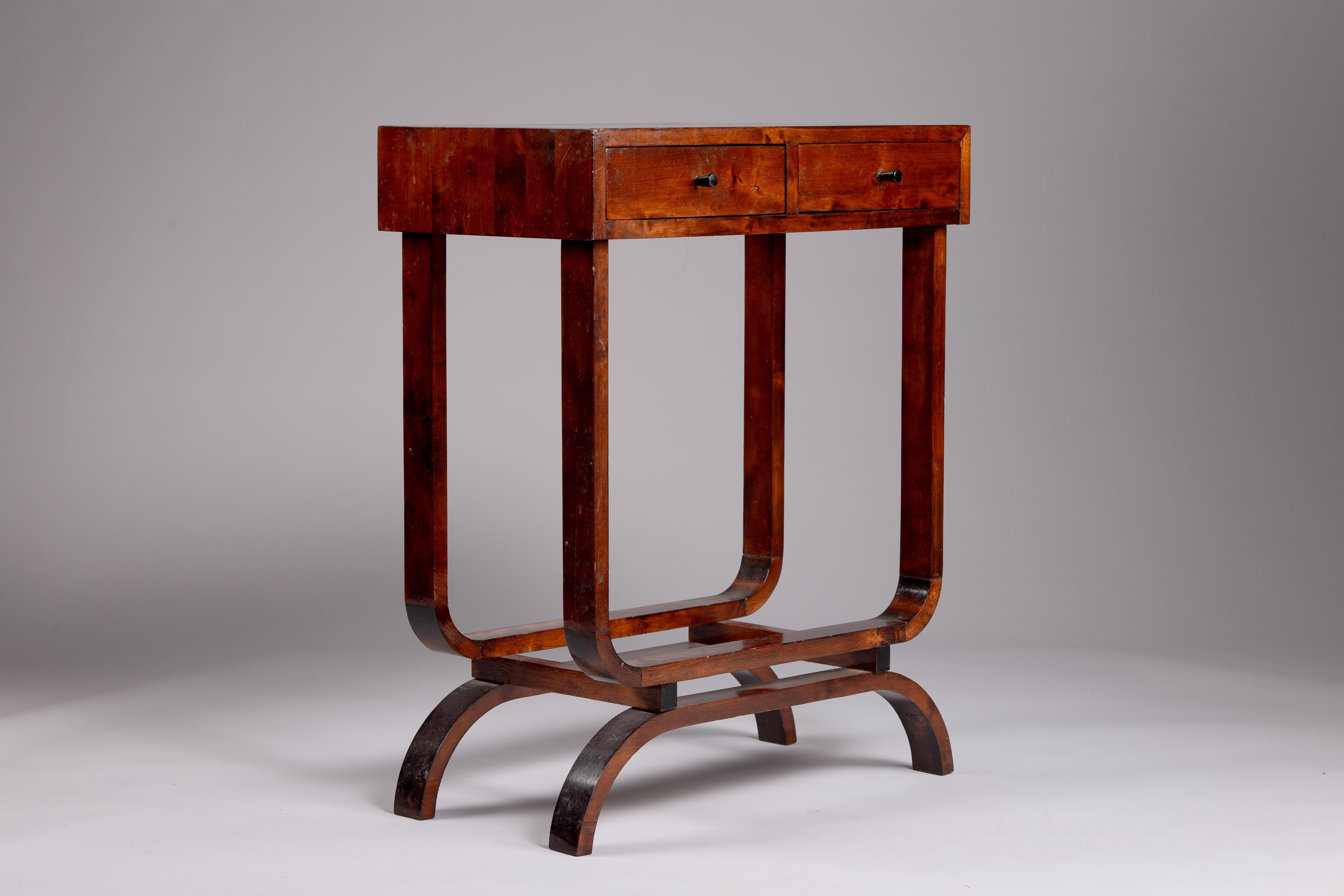 Crafted from exquisite flame birch, this Finnish 1930's accent table embodies the timeless elegance of Scandinavian vintage design. Featuring two functional drawers, it seamlessly blends form and function, offering both storage and style. The rich,