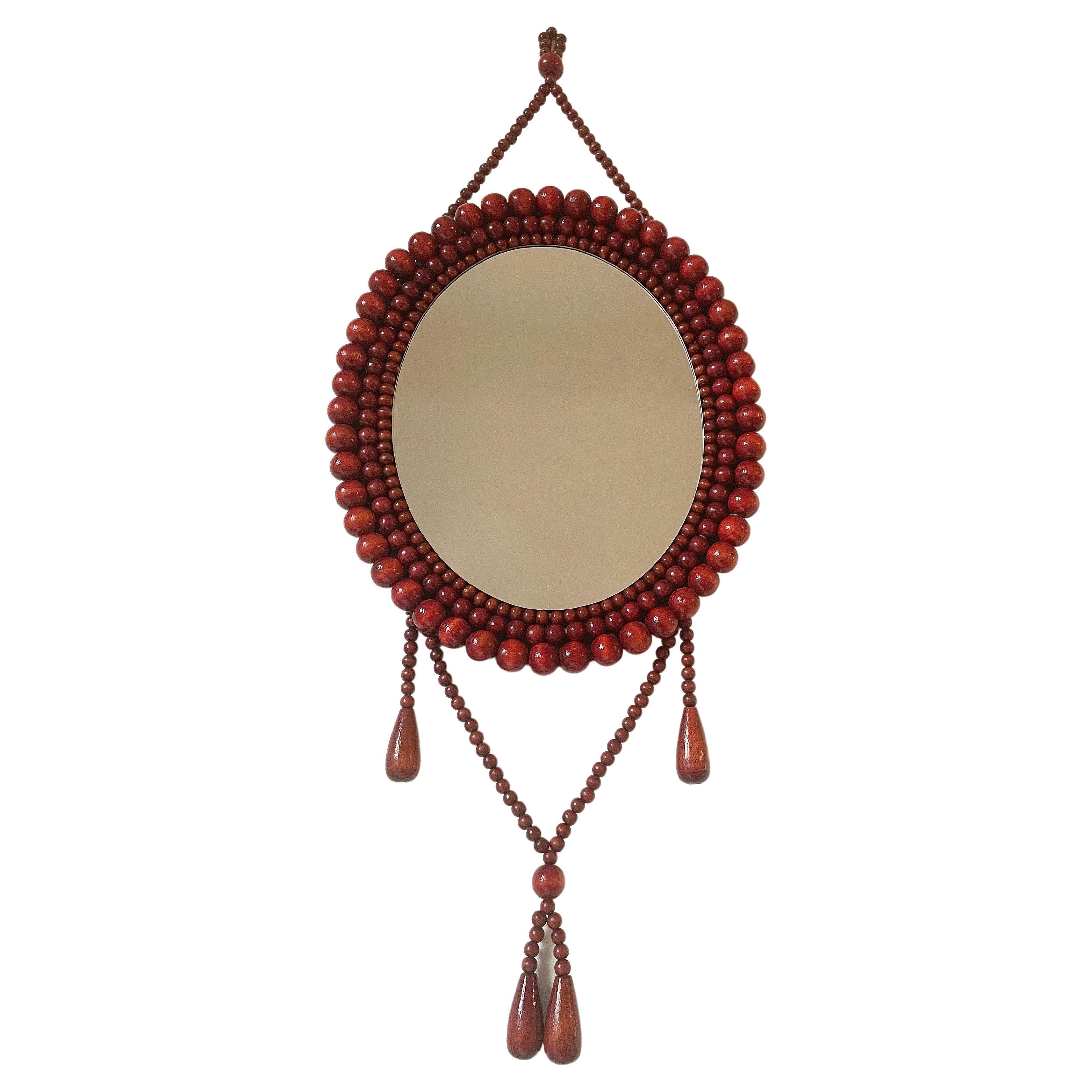 Finnish wall mirror in frame decorated with brown and mahogany shiny lacquered wooden beads in different sizes in the style of Aarikka. Mirror and beads in beautiful condition. Mounted on a wooden plate in matte dark brown. A Scandinavian midcentury