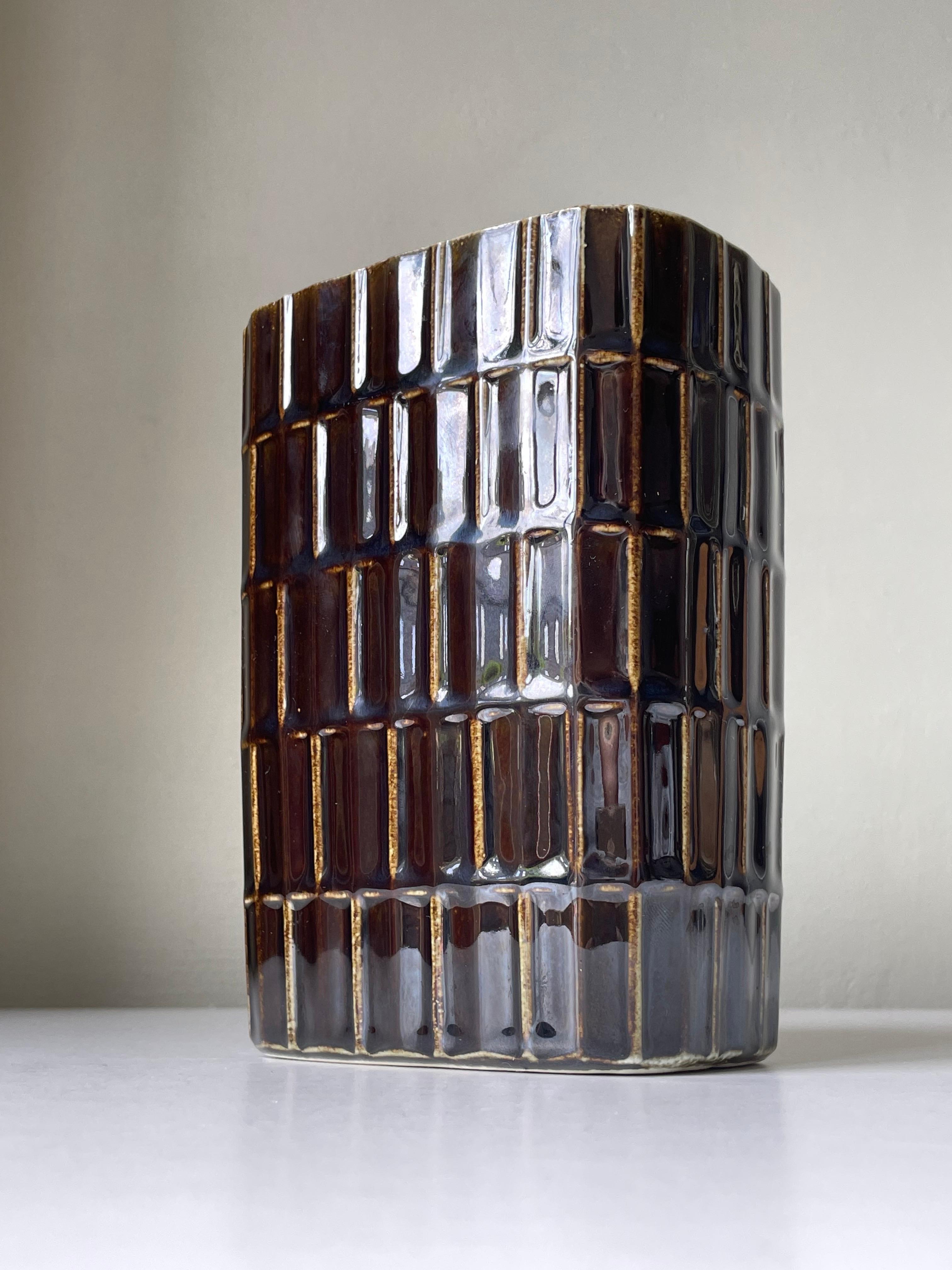 Scandinavian midcentury modern ceramic vase with chocolate and caramel brown colors on tiered geometric relief pattern. Designed by Göran Bäck for Finnish Arabia in the 1960s. Stamped under base. Beautiful vintage condition. 
Finland, 1960s. 