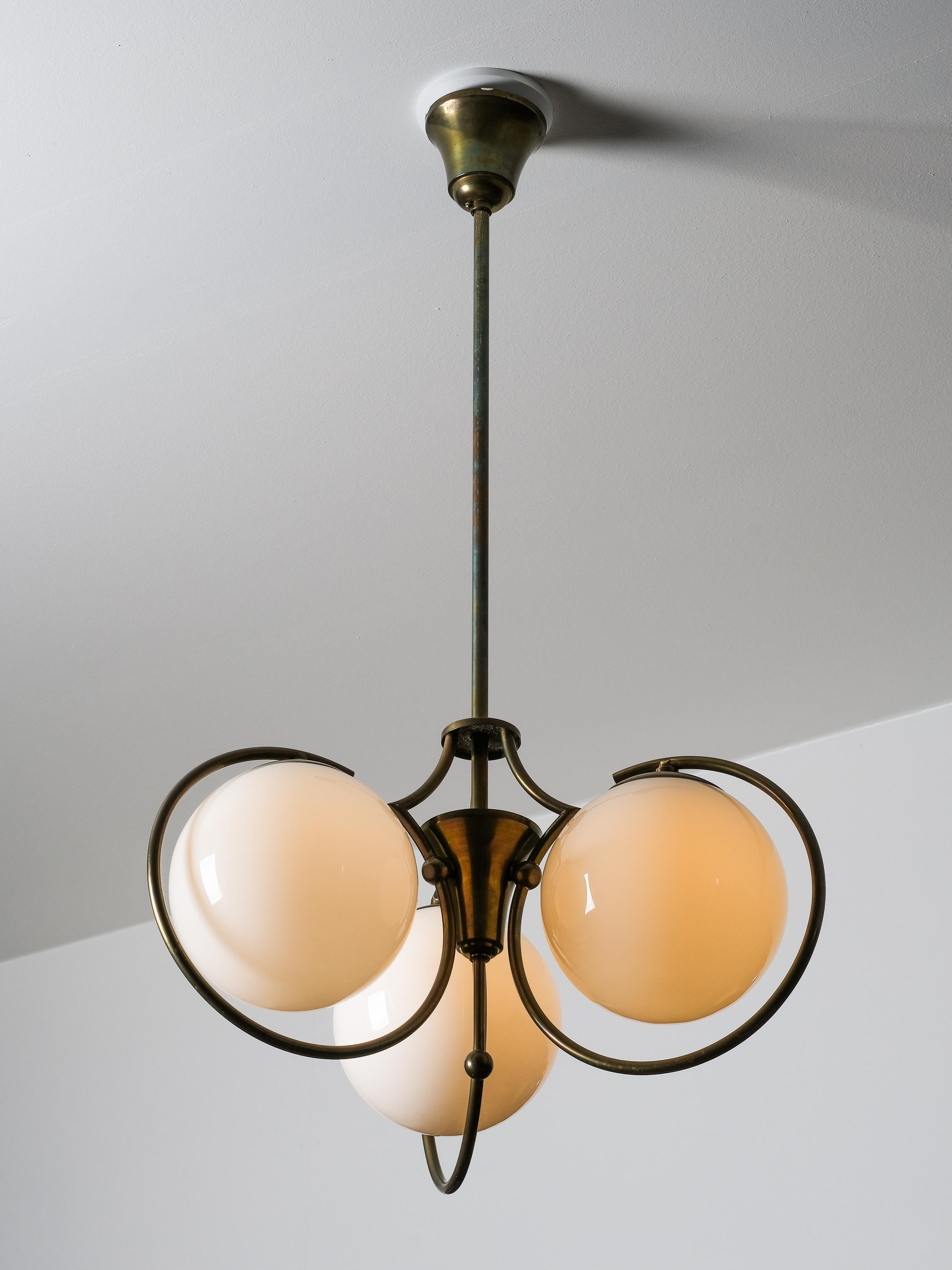 Questo elegante lampadario Art Deco è stato prodotto e progettato in Finlandia negli anni '30/'40.

La lampada presenta tre globi di vetro opalino e una ferramenta in ottone ossidato che le conferiscono un aspetto lussuoso e senza tempo. È un ottimo