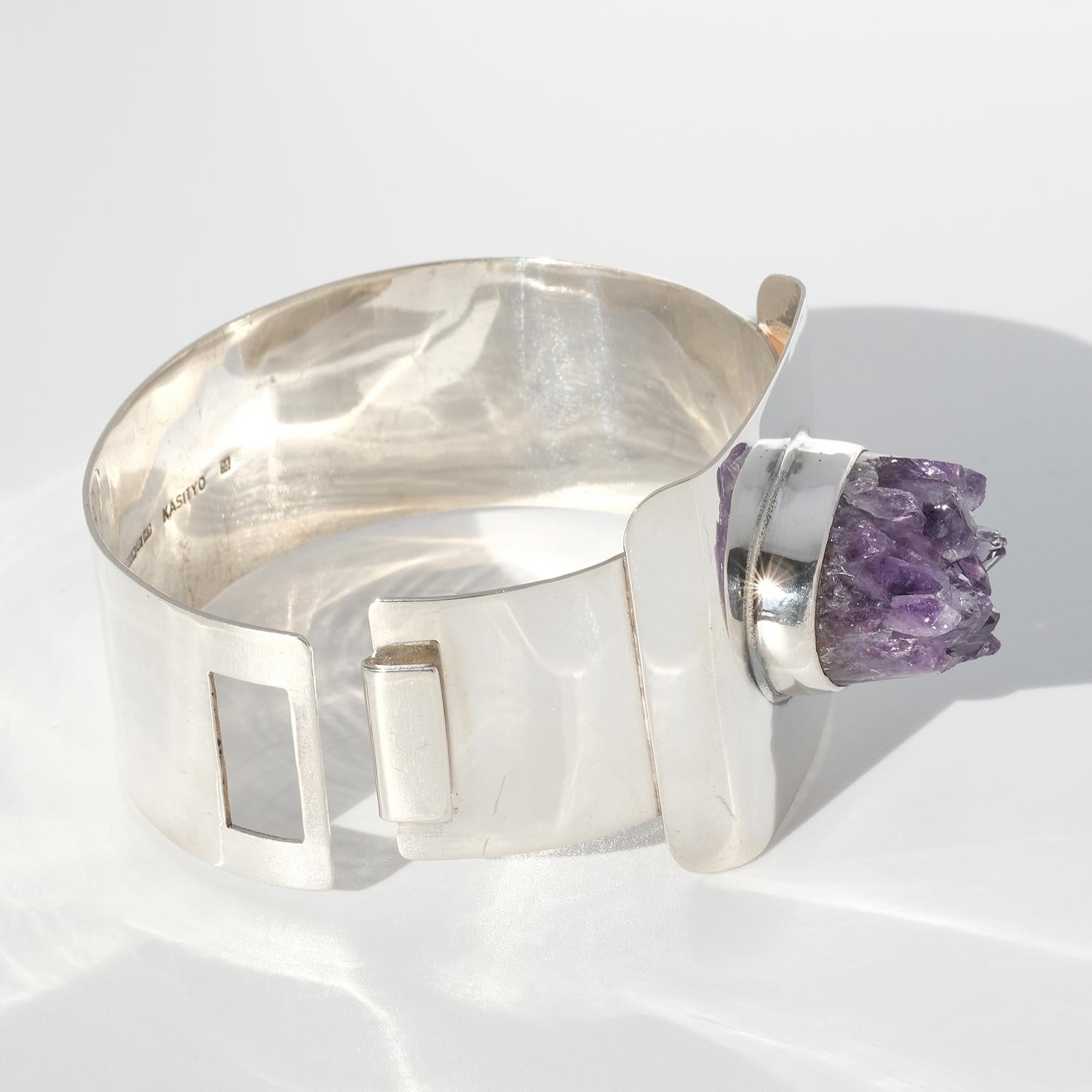 This handmade cuff silver bracelet looks, from above, like a belt buckle. It is adorned with an uniquely shaped amethyst, with pointing ends resembeling an active vulcano. It opens and closes with a practical hook-device.

This cuff bracelet is