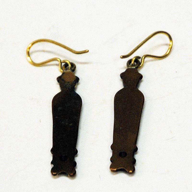 A special pair of bronze ear rings with peoples motive designed by Kirsti Ilvessalo for Kalevala Koru, Finland 1950s. The ear rings are of two similar women in straight up position and with old clothing. Hook fixings. 
Hallmarked on the back by
