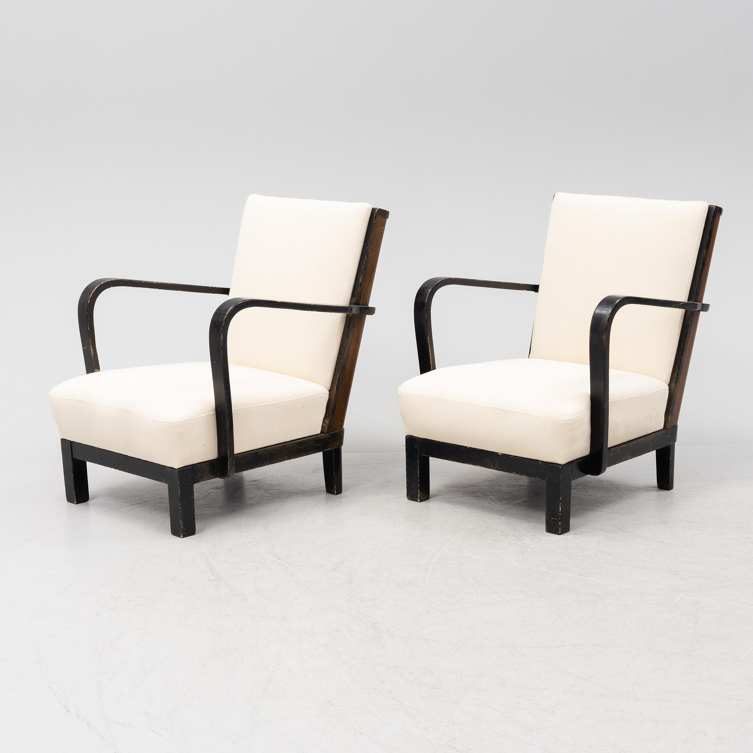 Finnish Lounge chairs produced by the manufacturer Asko Finland in 1935. The seats have been reupholstered in a sturdy Ivory Boucle fabric. The wood frame is  painted black and has some nice worn areas that form a striking contrast with the newly