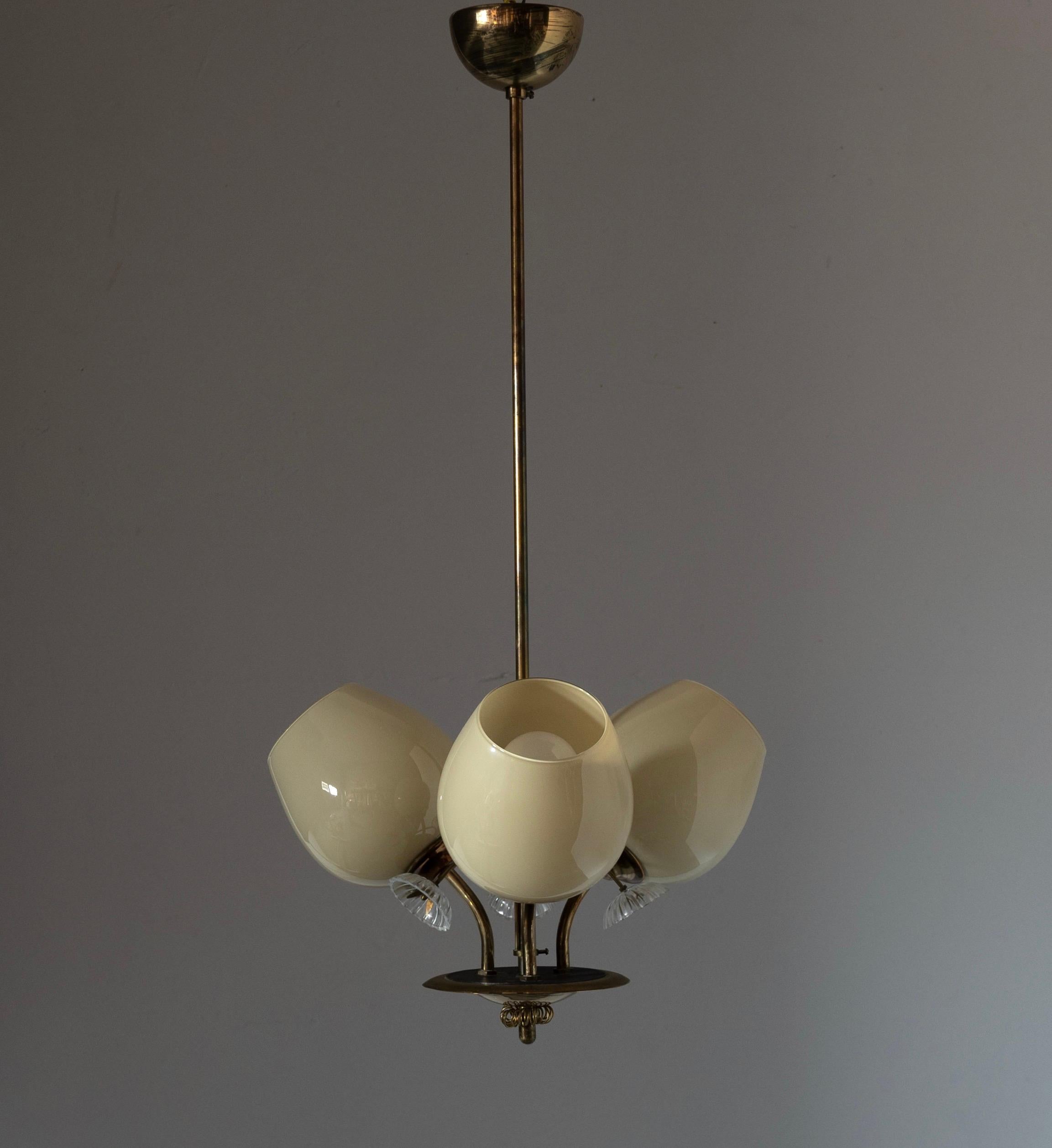 A chandelier light, designed and produced in Finland, 1940s. Features milk glass with organic ornamentation, blown glass, and finely detailed brass. 

Other designers of the period include Paavo Tynell, Alvar Aalto, Lisa Johansson-Pape, J.T.