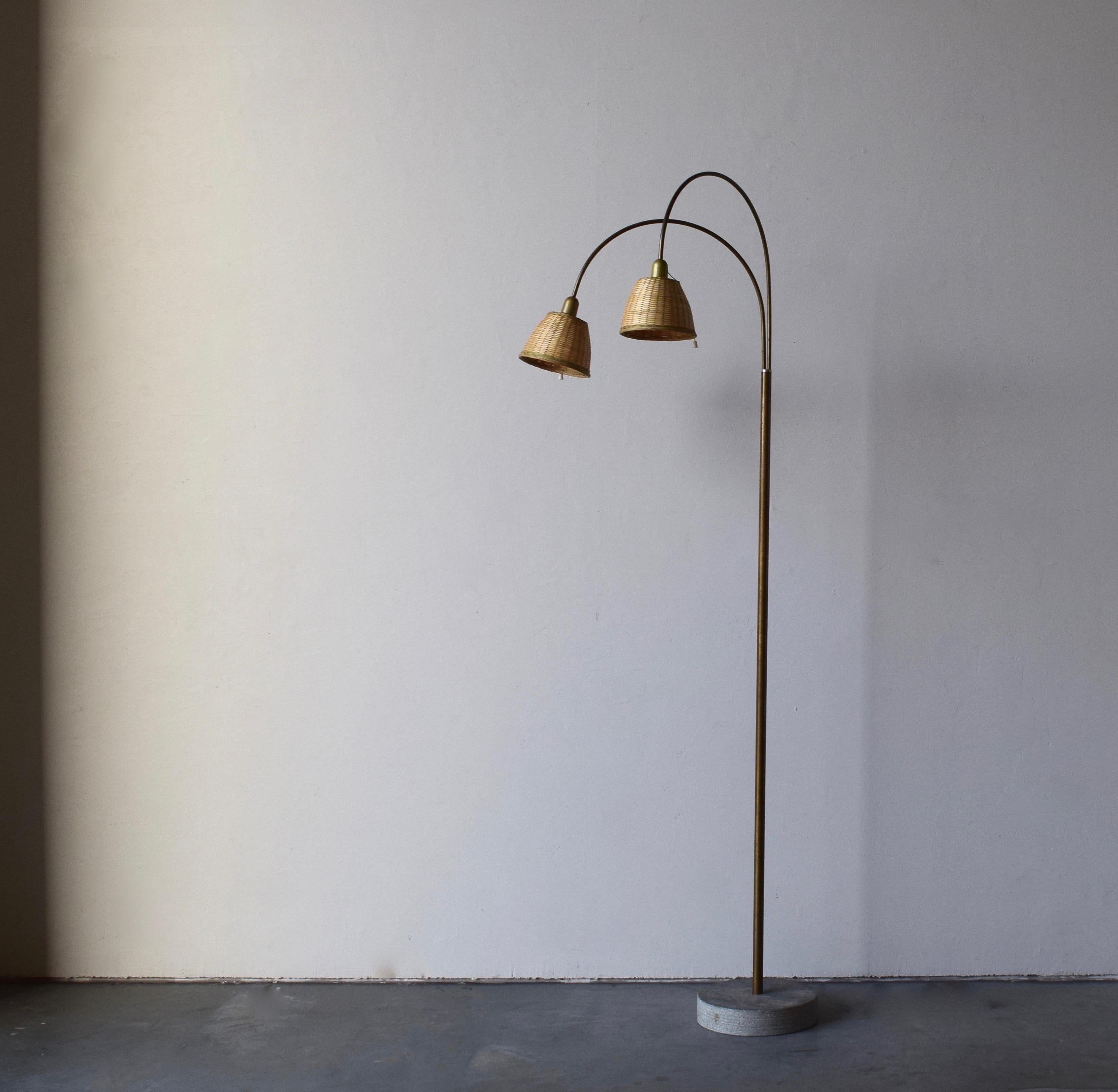 An adjustable two-armed floor lamp. Designed and produced in Finland, c. 1970s-1980s. Features brass, concrete, and assorted vintage rattan lampshades.

Stated dimensions measured as is illustrated in the third image.