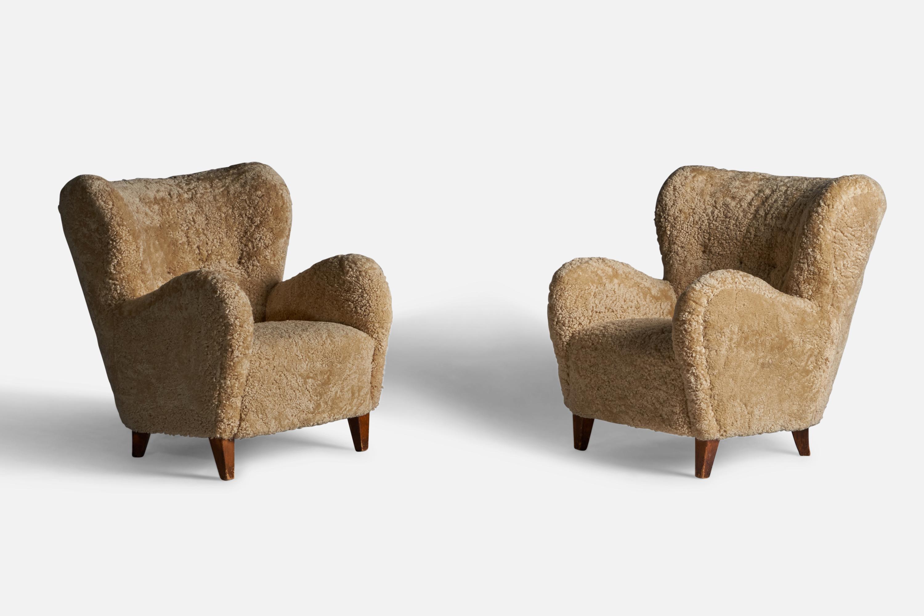A pair of organic shearling and stained birch lounge chairs, designed and produced in Finland, 1940s.
