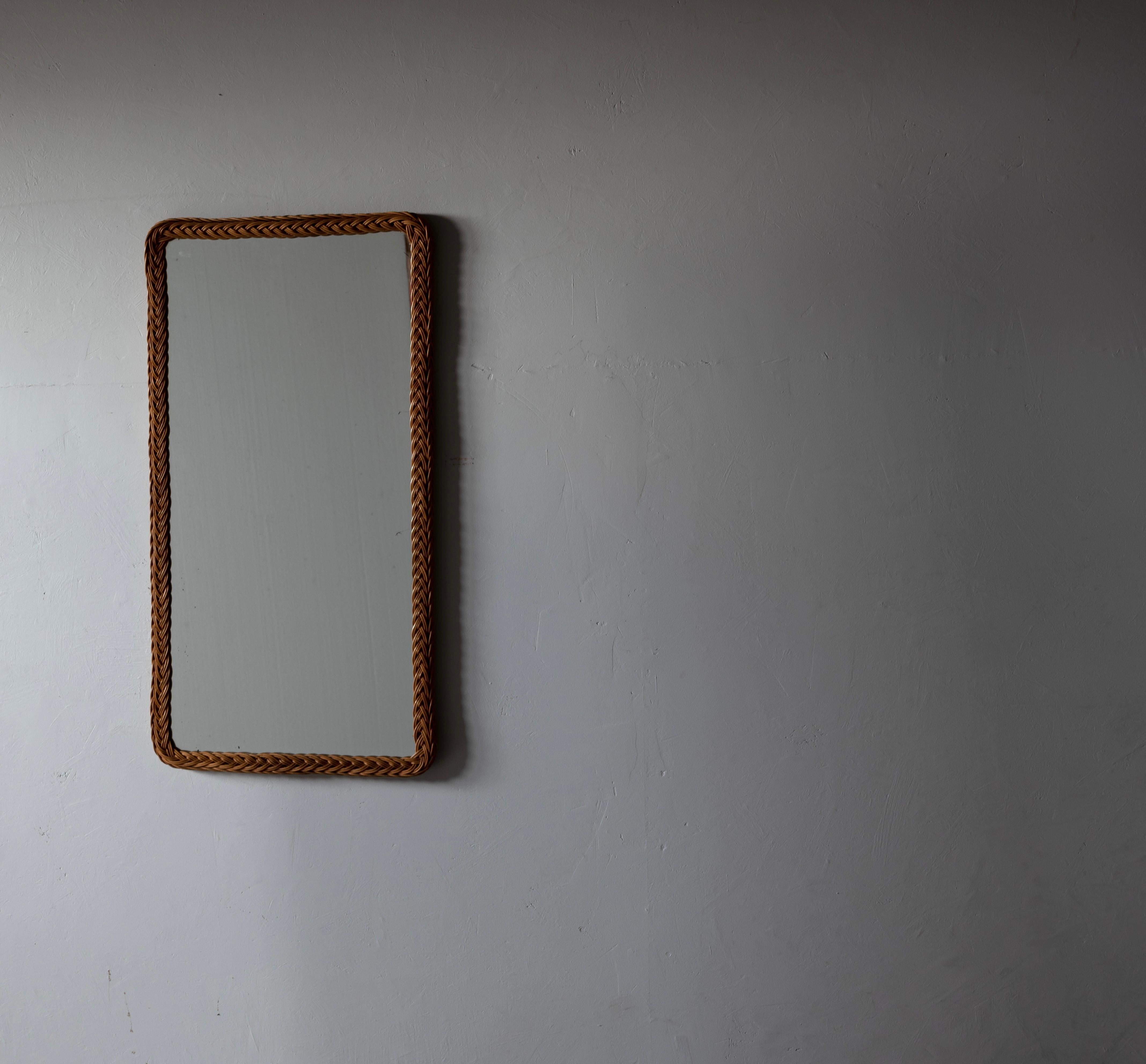 A wall mirror with its original mirror glass, solid teak frame. Produced in Finland, 1950s. Frame is wrapped in rattan.

    