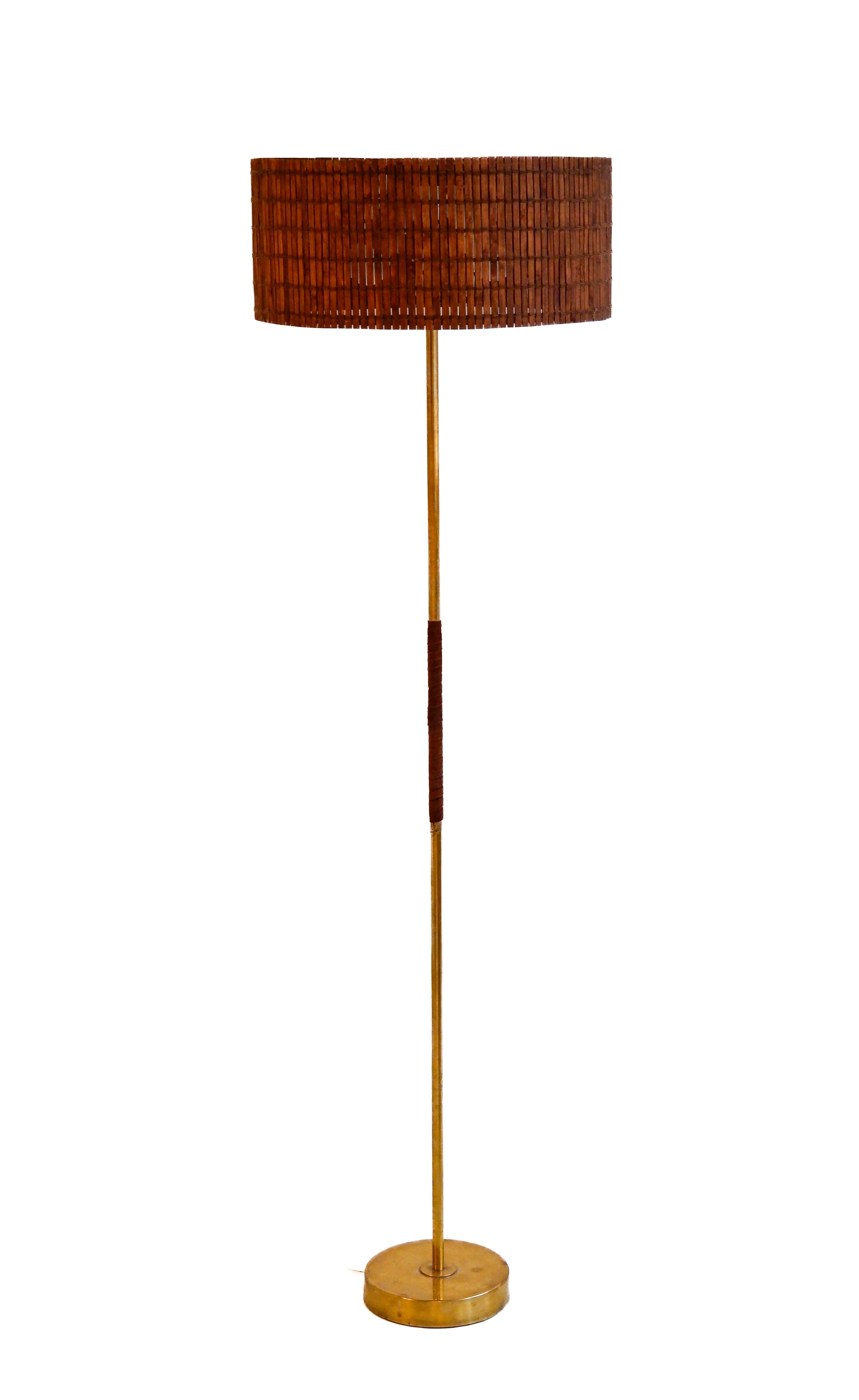 Finnish vintage floor lamp designed and produced by the light factory Presenta in the 60's. The lamp is made in solid brass, has a leather detail on its core and a rattan shade. Good overhall condition ! The lamp is stamped by the editor Presenta.