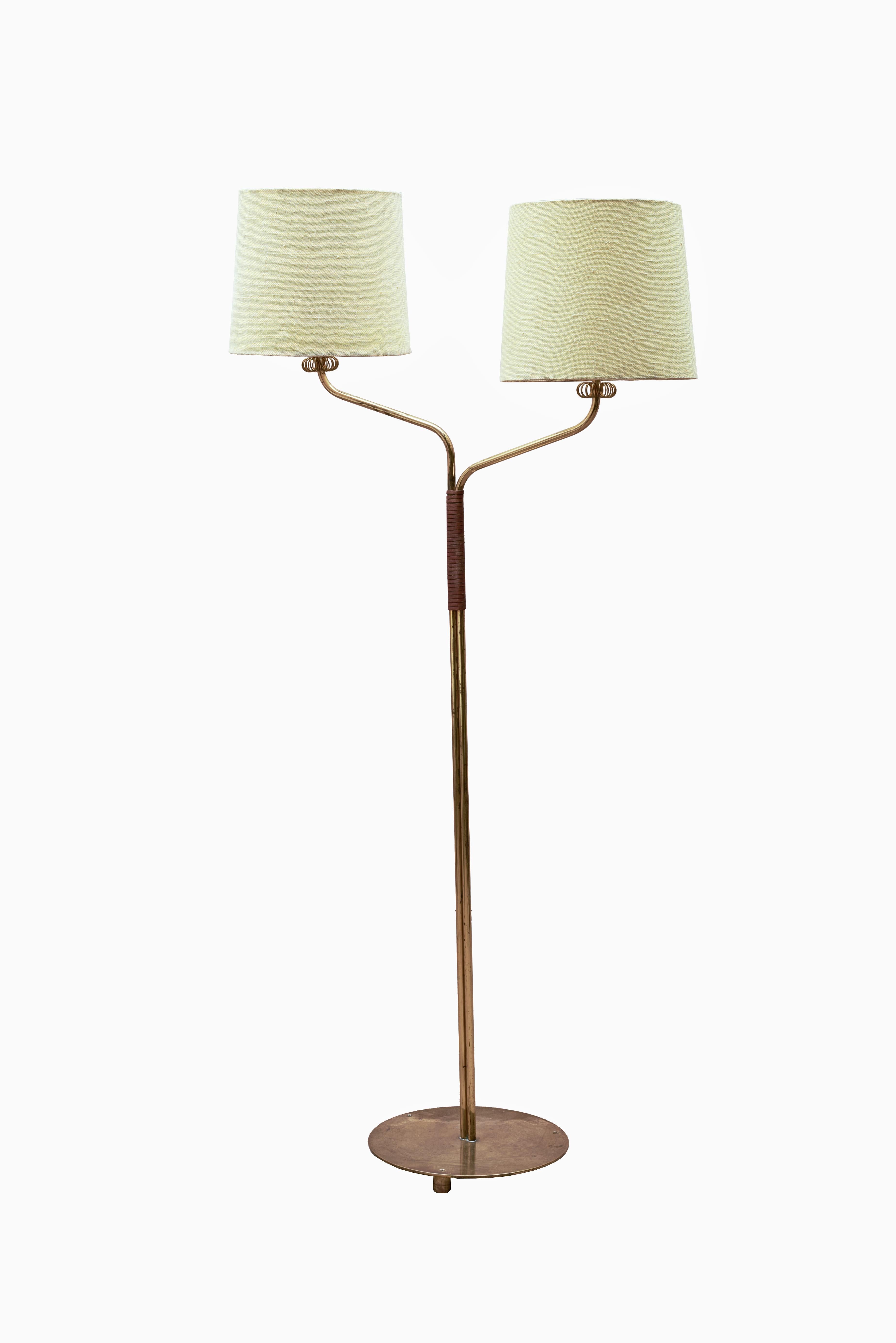 A truly remarkable Finnish Brass Floor Lamp that combines exquisite craftsmanship with versatile functionality. This stunning lamp features two shades of textured woven fabric, a stunning brass frame, and intricate leather cording details. This