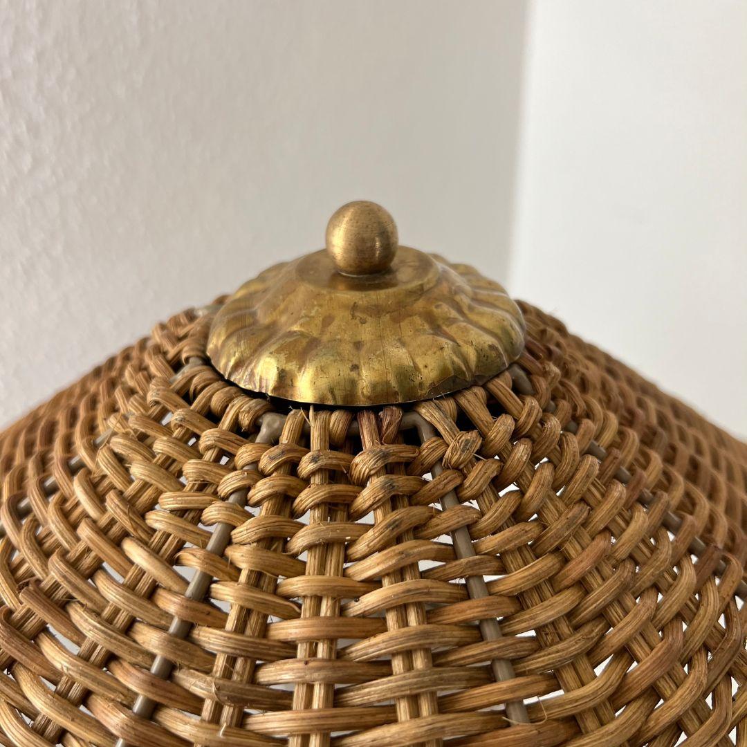 Finnish floor lamp from the 1960s. A unique floor lamp with a woven lampshade, accented with a small brass detail. The lamp's column features a twisted plastic thread running along its length, while the base is made of painted wood.