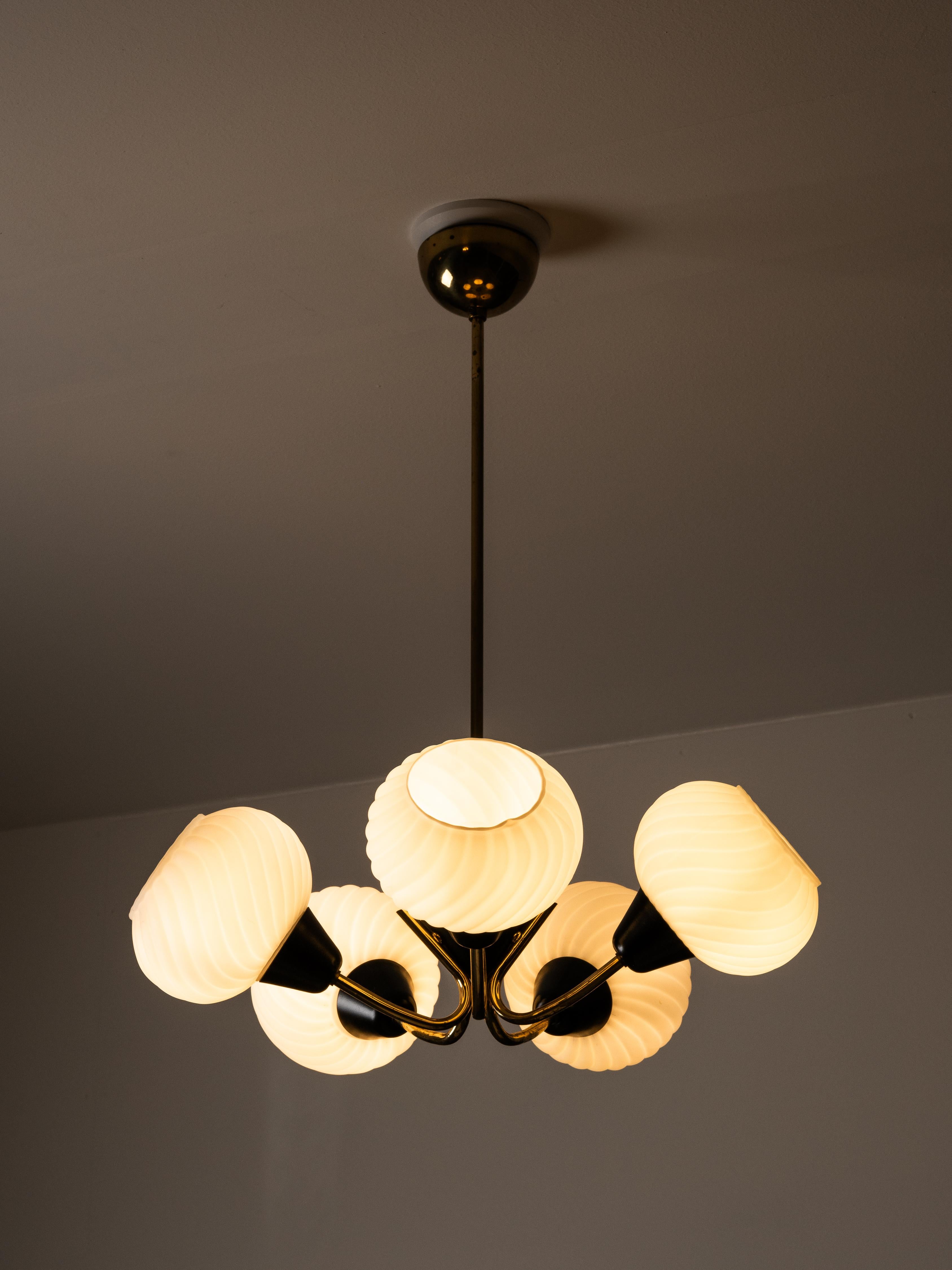 A beautifully crafted Finnish mid-century chandelier featuring five opaline, swirl-patterned glass shades paired with a brass and black-lacquered metal frame. The combination of sculptural, curved brass arms and deeply textured white glass globes
