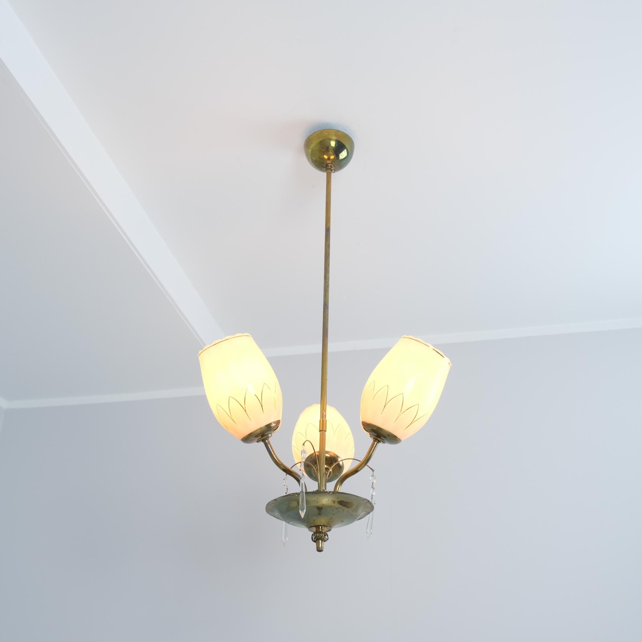 Suspension de plafond finlandaise de style moderne du milieu du siècle, modèle 62-402/3 du catalogue Stockmann. La lampe est composée d'un corps en laiton avec un bol décoré et perforé avec des décorations en cristal et en verre. Le modèle comporte
