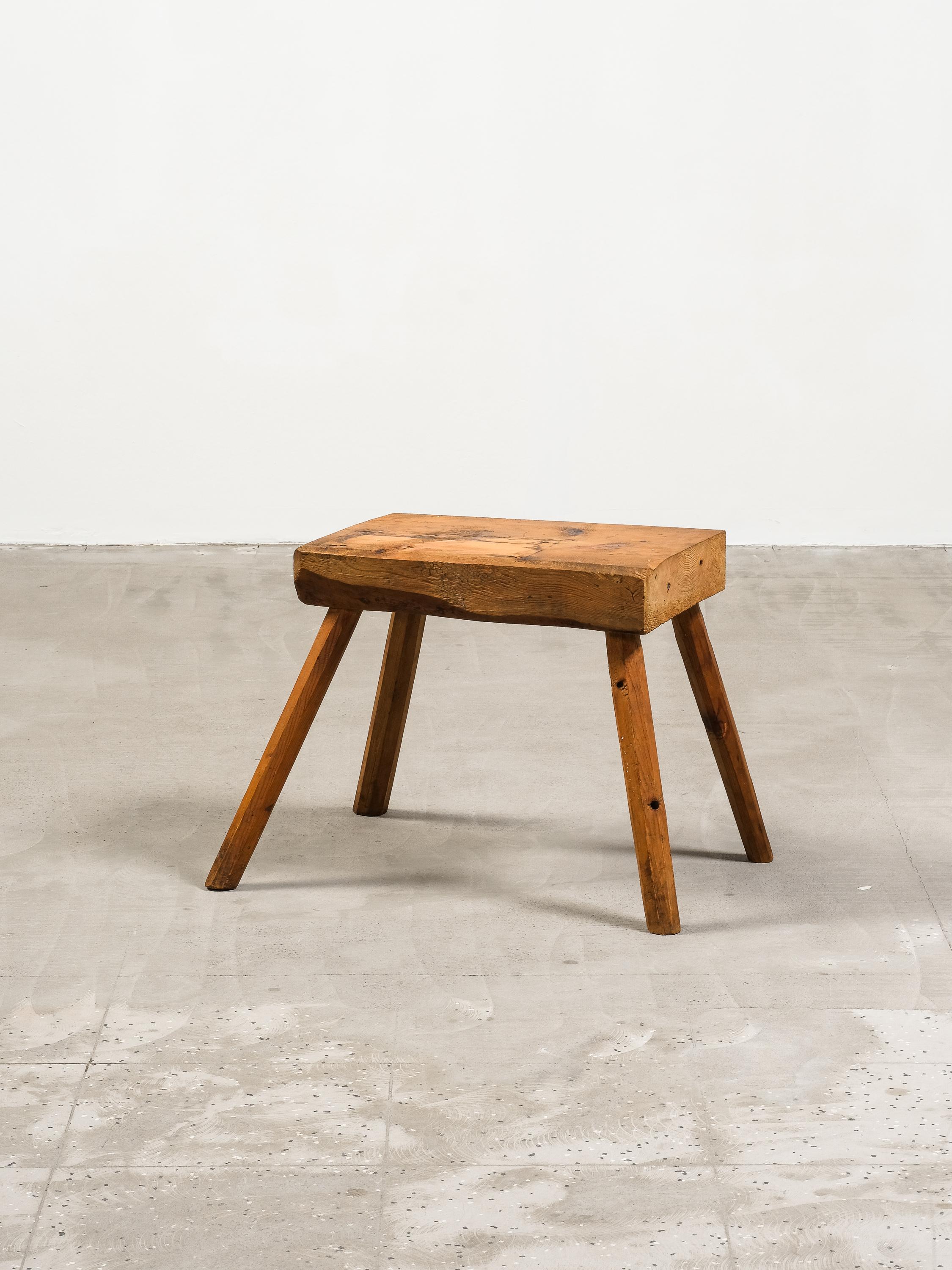 Un affascinante sgabello rustico di arte popolare proveniente dalla Finlandia, risalente alla fine del XIX o all'inizio del XX secolo. Realizzato in pino massiccio, questo pezzo trasuda artigianato vernacolare con la sua estetica grezza e sbozzata a