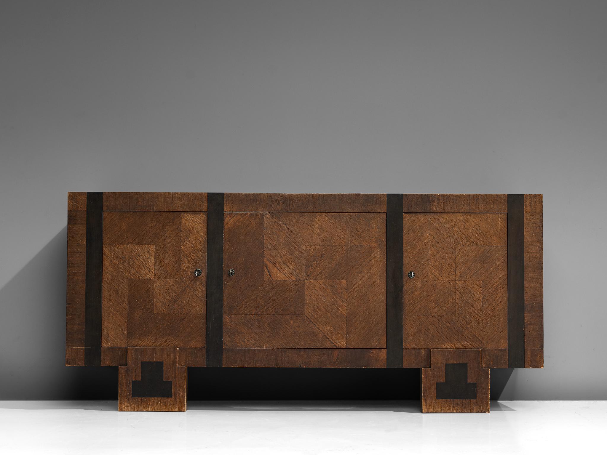 Sideboard or credenza, oak, brass, Finland, 1930s 

This sideboard of Finnish origin is characterized by a cubic shaped construction inlayed with dark vertical lines and a pattern of stained oak inlays. Therefore, the front gets an appealing,