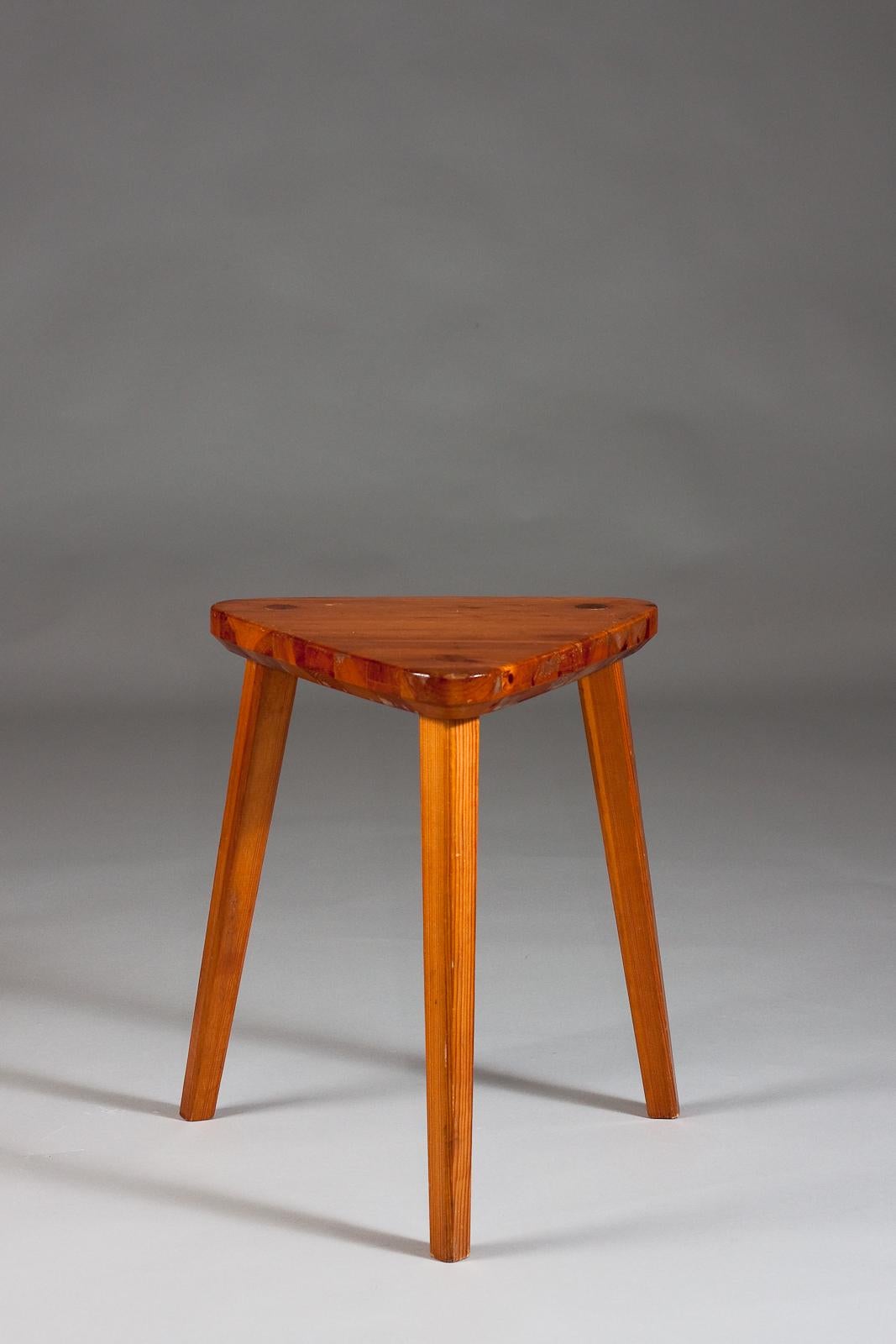 This exquisite three-legged stool, crafted from robust pine wood, embodies the essence of Scandinavian Vintage Design. The intriguing triangular seat showcases a rich patina that speaks to its timeless charm. Perfect for adding a touch of rustic