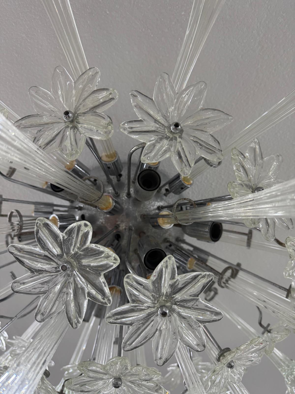 This extraordinary 1960s chandelier is a masterpiece by Paolo Venini, an emblem of Murano glass excellence applied to Mid-Century design. The central chrome-plated metal frame accommodates a constellation of transparent blown glass elements molded