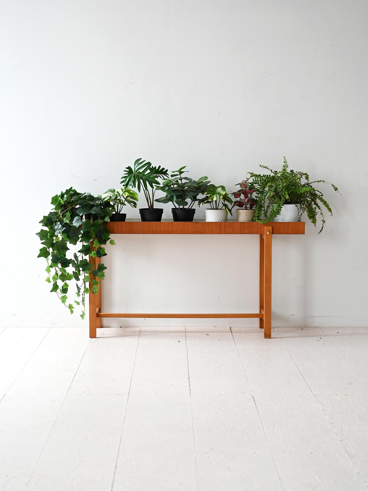 Scandinavian teak planter with essential structure and metal inner basin. Linear legs with brass details.

Vintage Scandinavian planter made of teak, with a rectangular compartment designed to hold plants or flowers. The interior has a removable