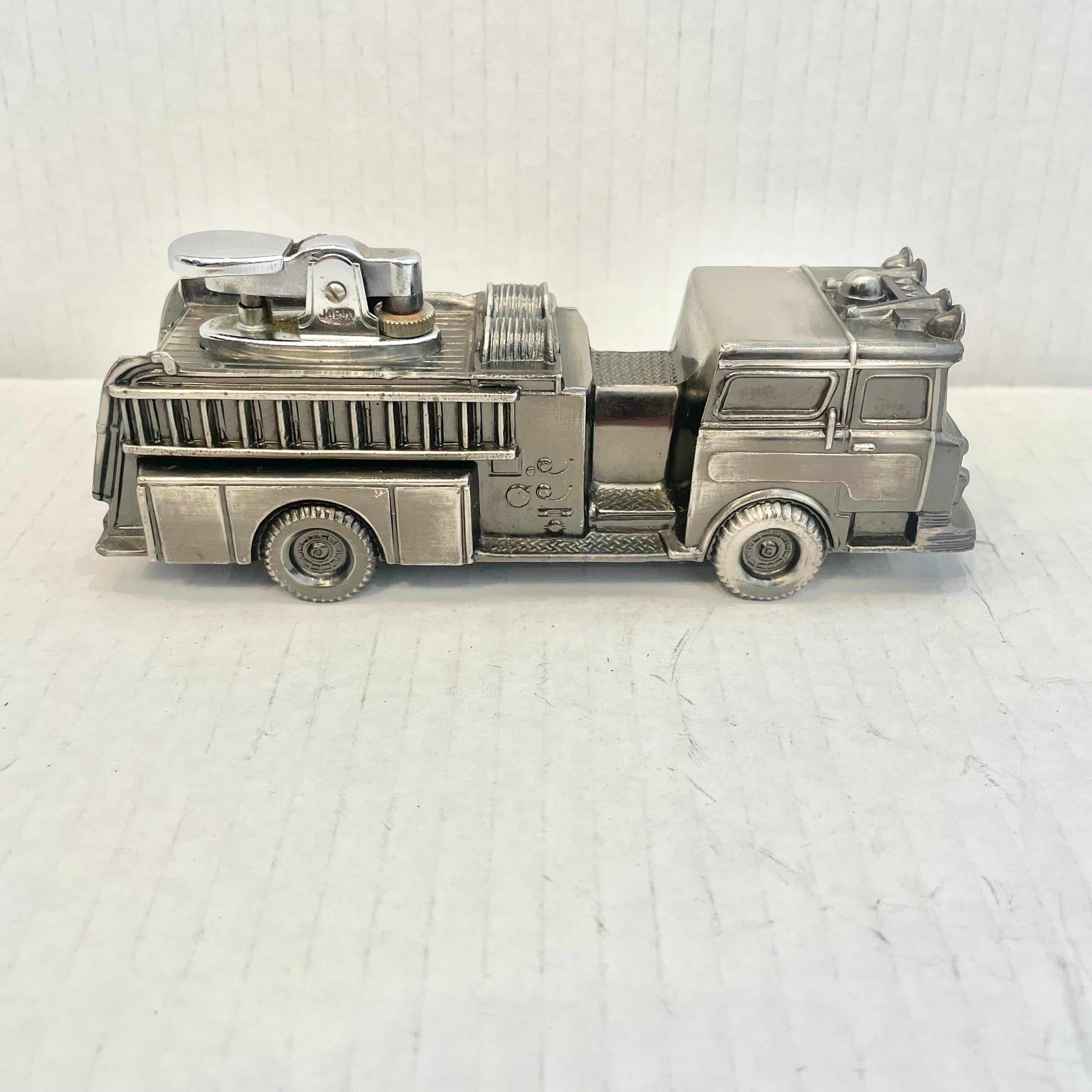 Cool vintage table lighter in the shape of a fire engine. Made completely of metal with a hollow body. Beautiful burnished silver color with intricate details. Cool tobacco accessory and conversation piece. Working lighter. Very unusual piece. Made