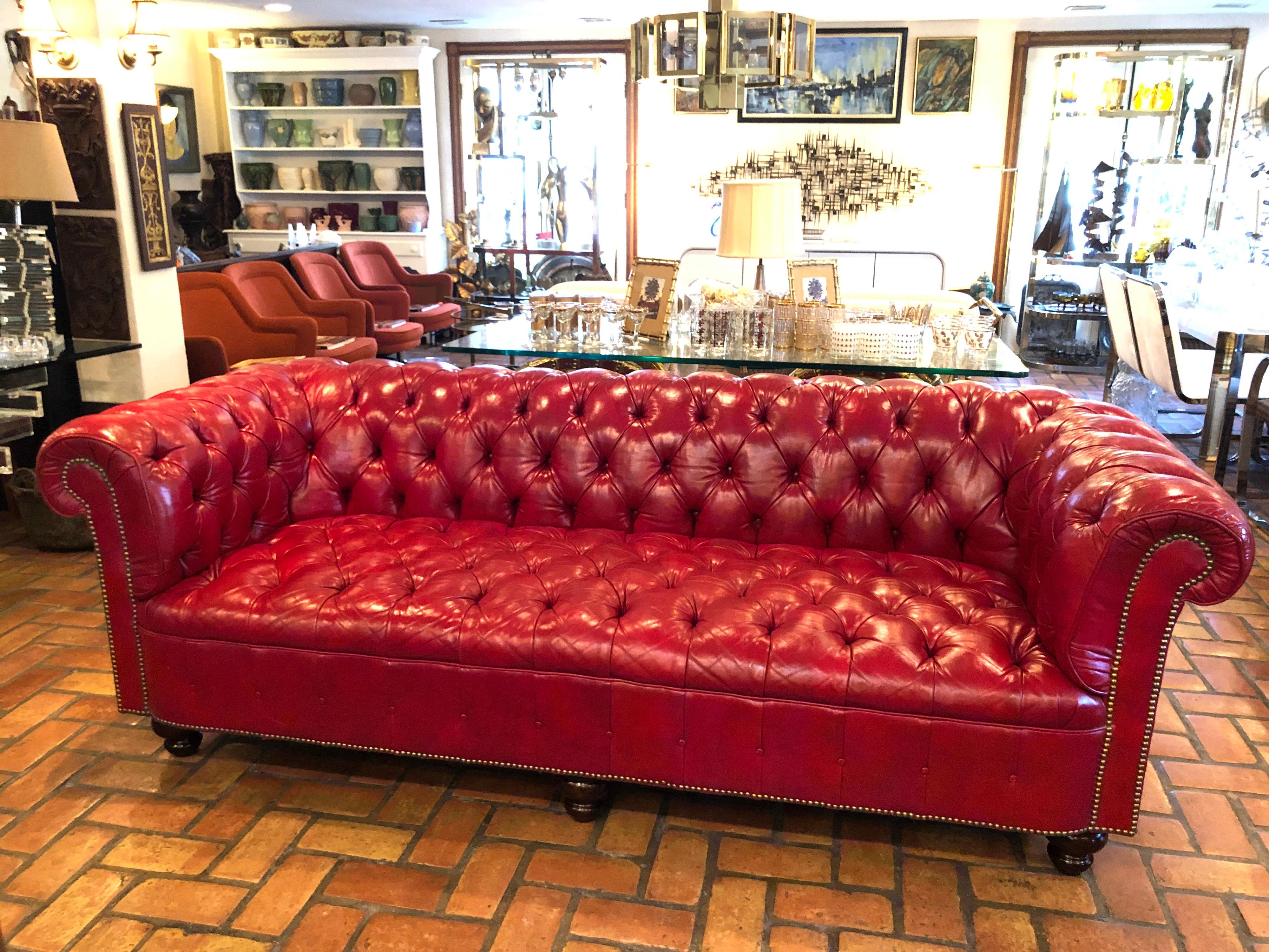 Fire engine red leather chesterfield. Beautiful tufted leather in very good condition with wooden ball feet and brass tacks all around. . Classic style and design. Perfect for a study or a library.