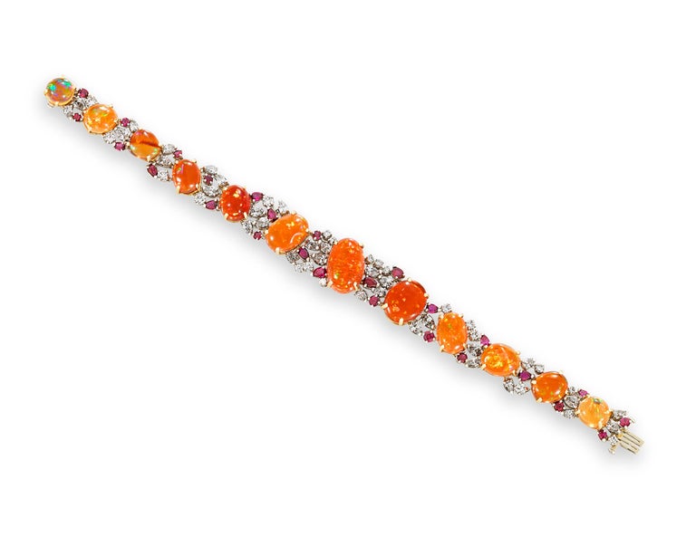 This breathtaking bracelet features 12 brilliant fire opal cabochons totaling 37.91 carats displayed in a beautiful design by Oscar Heyman. An eye-catching array of crimson rubies weighing 4.25 carats and white diamonds weighing 4.98 carats