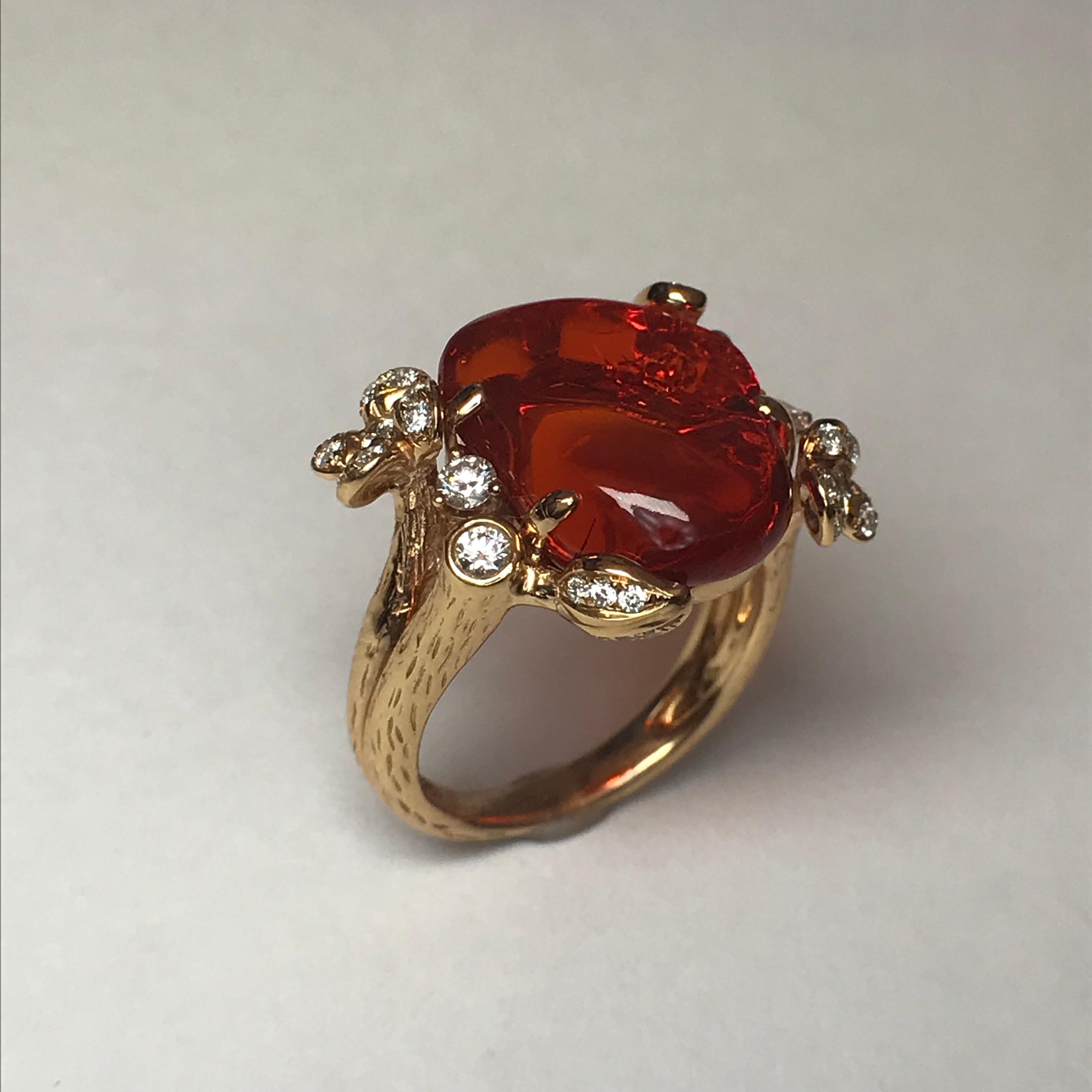 A unique hand-carved crimson red fire opal provides the visual warmth to make this ring bloom. The warm rose gold is patterned with a bark texture and sprouts diamond flowers and leaves.

Free-Form Fire Opal: 6.20cts.
Round Brilliant-Cut Diamonds: