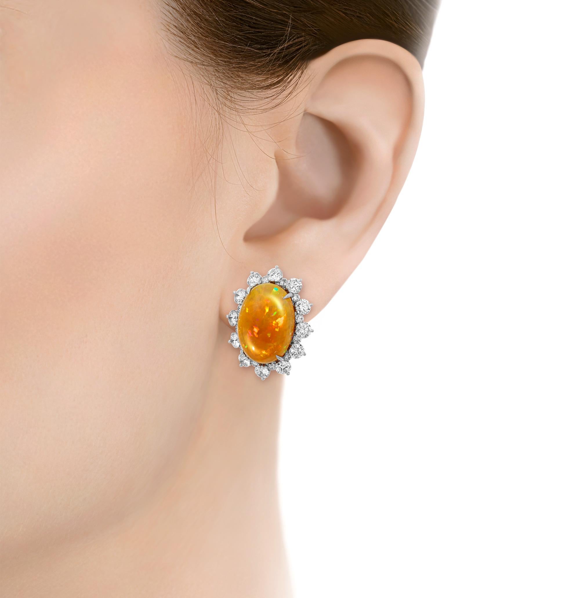 A stunning interplay of fire and ice, two perfectly matched cabochon fire opals coalesce with sparkling diamonds to form these statement earrings. Totaling an impressive 13.40 carats, the fire opals display the bold orange and golden hues for which