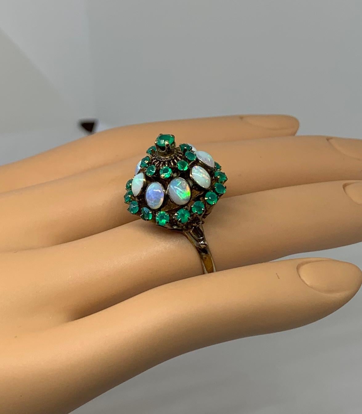 THIS IS A WONDERFUL ART DECO OPAL AND EMERALD PRINCESS RING OF GREAT BEAUTY.
The ring is a tall bombe princess ring.  It is set with eight magnificent opals.   Along with the opals are 25 sparkling green emeralds.  The effect of the gorgeous natural