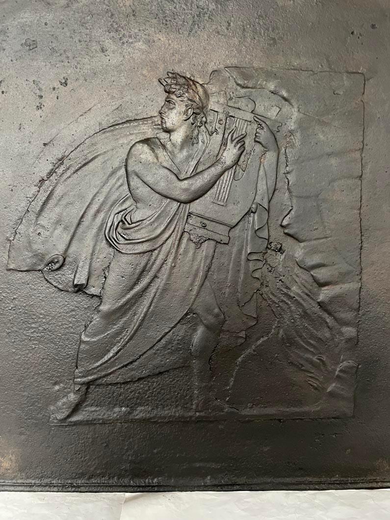 Dieser Kaminboden wurde im 19. Jahrhundert aus Gusseisen hergestellt. Es ist mit einer Darstellung des Gottes Apollo geschmückt, die wir an der Leier erkennen, die er in den Händen hält.