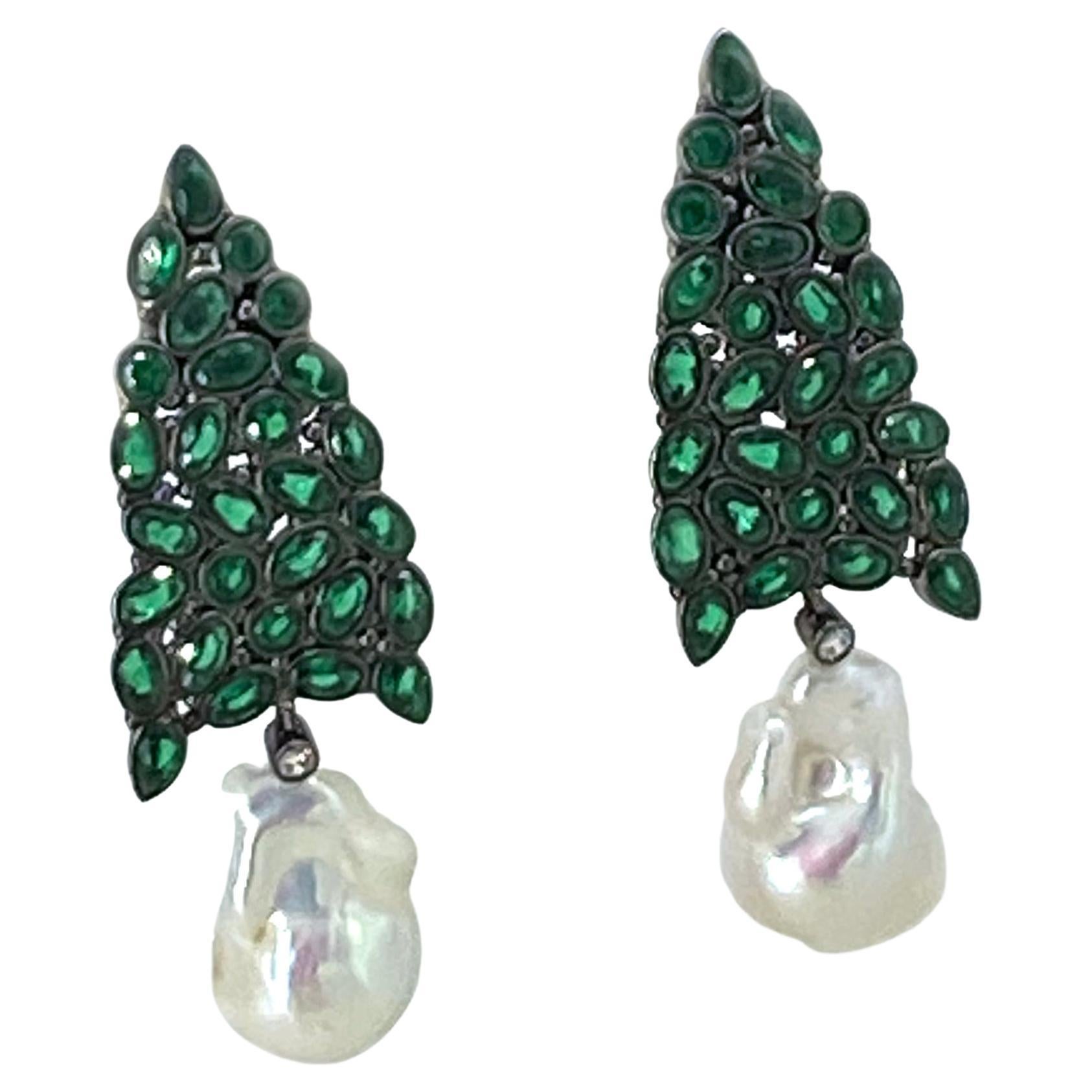 Si tratta di un paio di orecchini a goccia con perla barocca fireball e CZ verde. Ci sono cluster di CZ di forma ovale e rotonda incastonati in alberi di Natale aperti in argento sterling placcato oro nero. I pendenti con perle fireball bianche