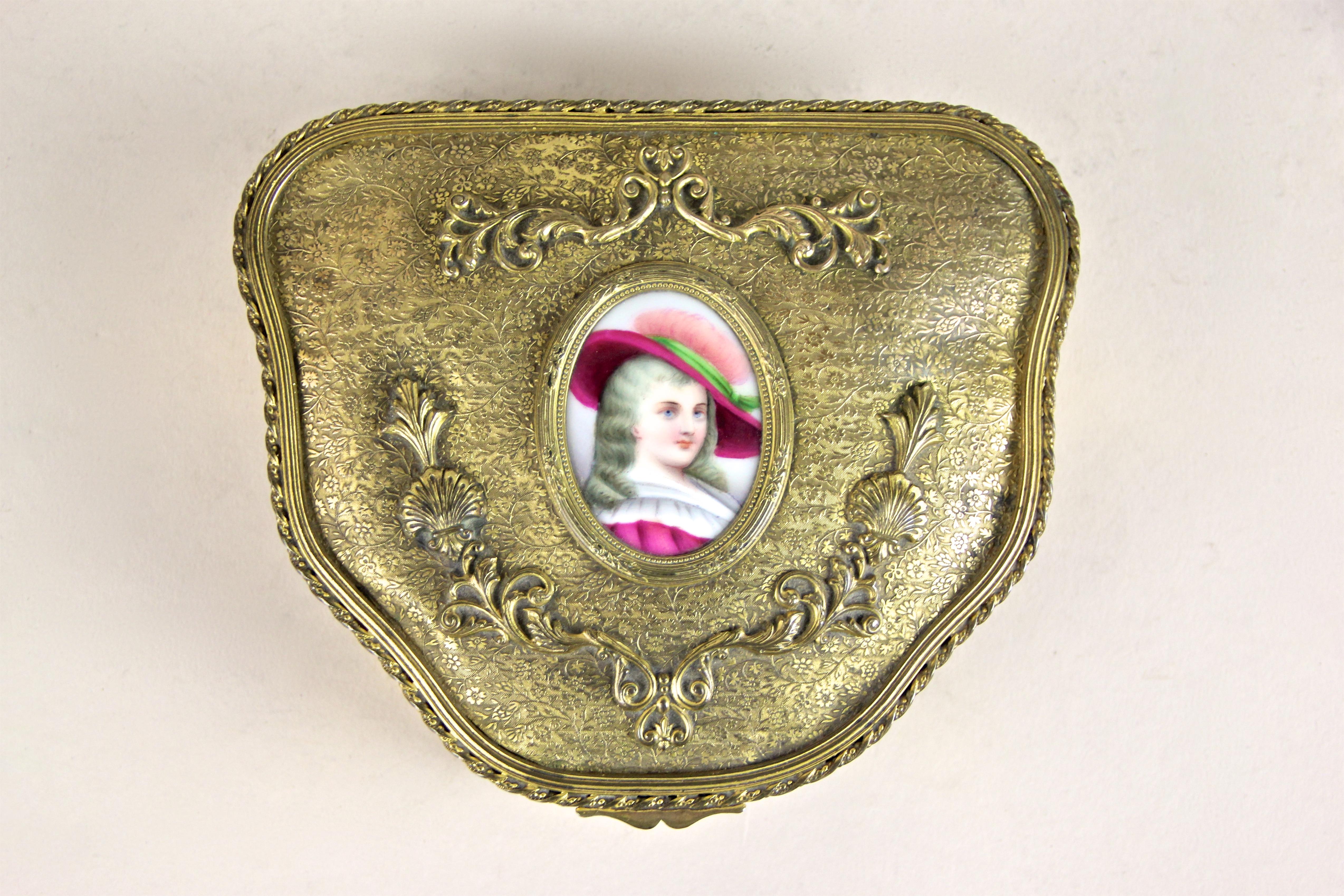 Unique firegilt brass jewelry box with porcelain picture from Austria, circa 1860. The artfully made box from the mid-19th century impresses with an amazingly detailed surface adorned by beautiful flowers or floral elements. The center of the hinged