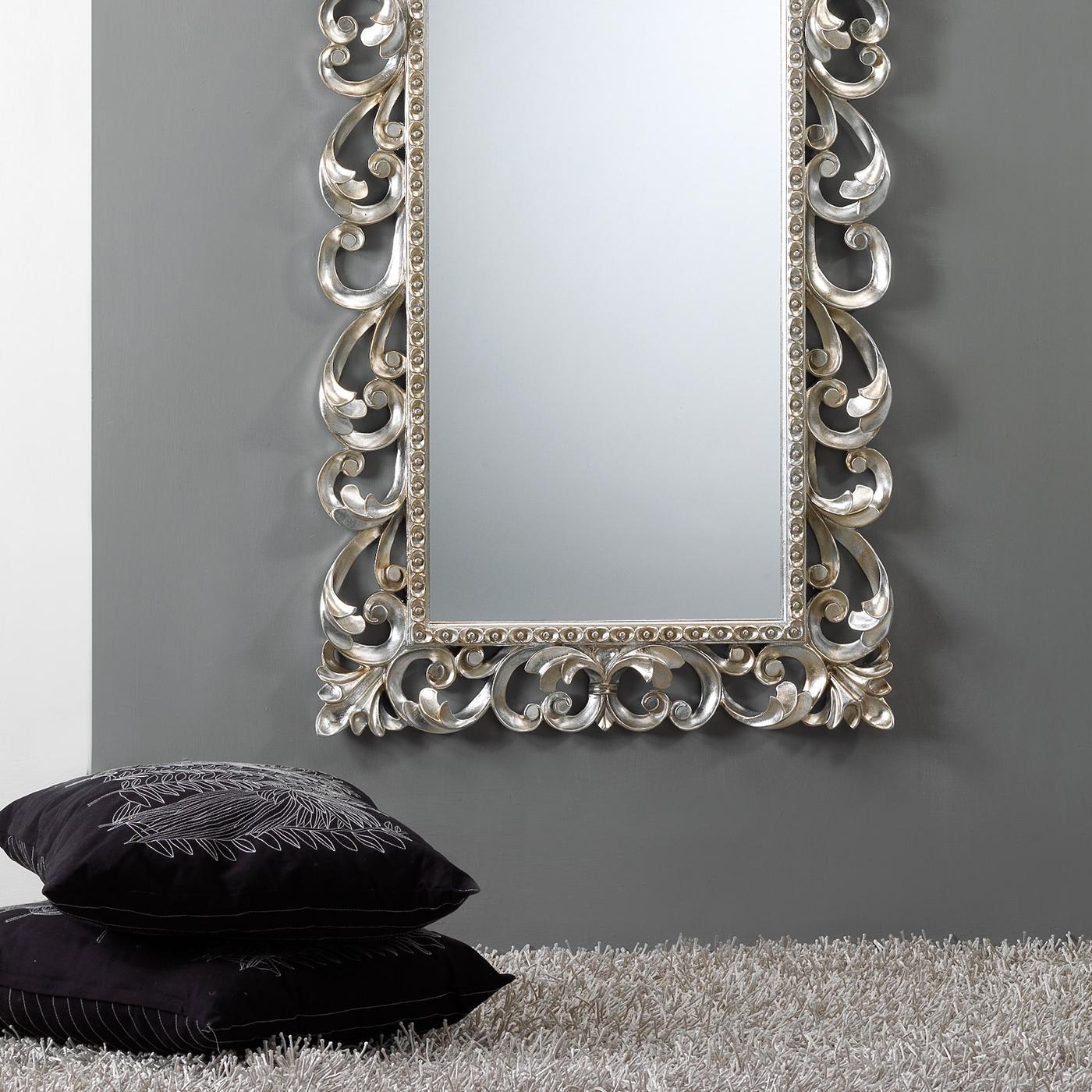 Brimming with timeless sophistication, this exquisite wall mirror strikes with the decoration of curved acanthus leaves inlaid in the solid wood frame. Finished by hand by applying a slightly antiqued, champagne-colored silver leaf, the frame