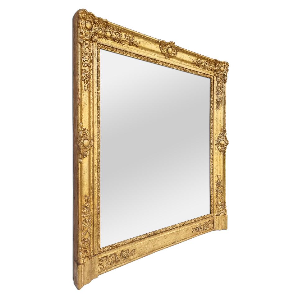 Antique fireplace mirror, French Restoration period, circa 1820. Antique giltwood frame, re-gilding to the leaf patinated, adorned with stylised shells and plant decorations (Antique frame width measures: 9.5 cm / 3.74 in). Modern glass mirror.