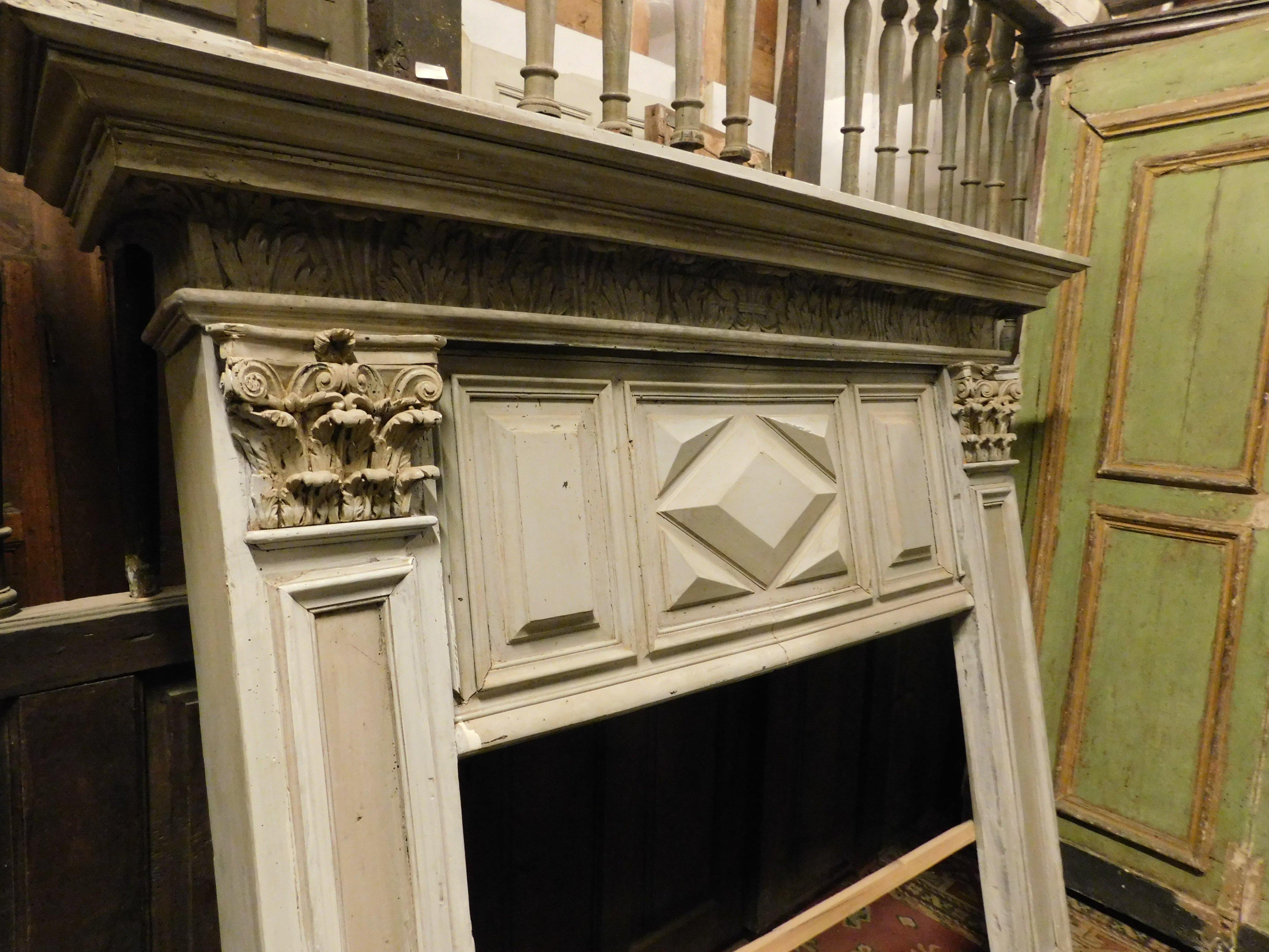 Antique old vintage fireplace mantle, built in solid poplar wood, hand lacquered in single color grey, enriched with sculpted tiles, has a sculpted pediment with geometric decorations. Legs with sculpted columns and capitals, built in the 19th