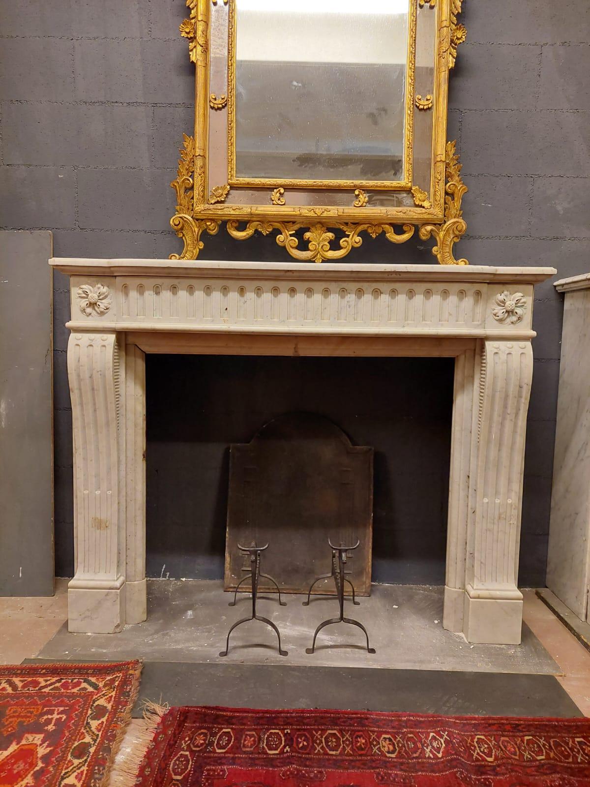 Antique fireplace mantle, hand-sculpted in precious and solid white Carrara marble, carved with lateral flowers and typical decorations on the sides and pediment, from France from the 18th century, maximum dimensions cm W 136 x H 107 x D 41,