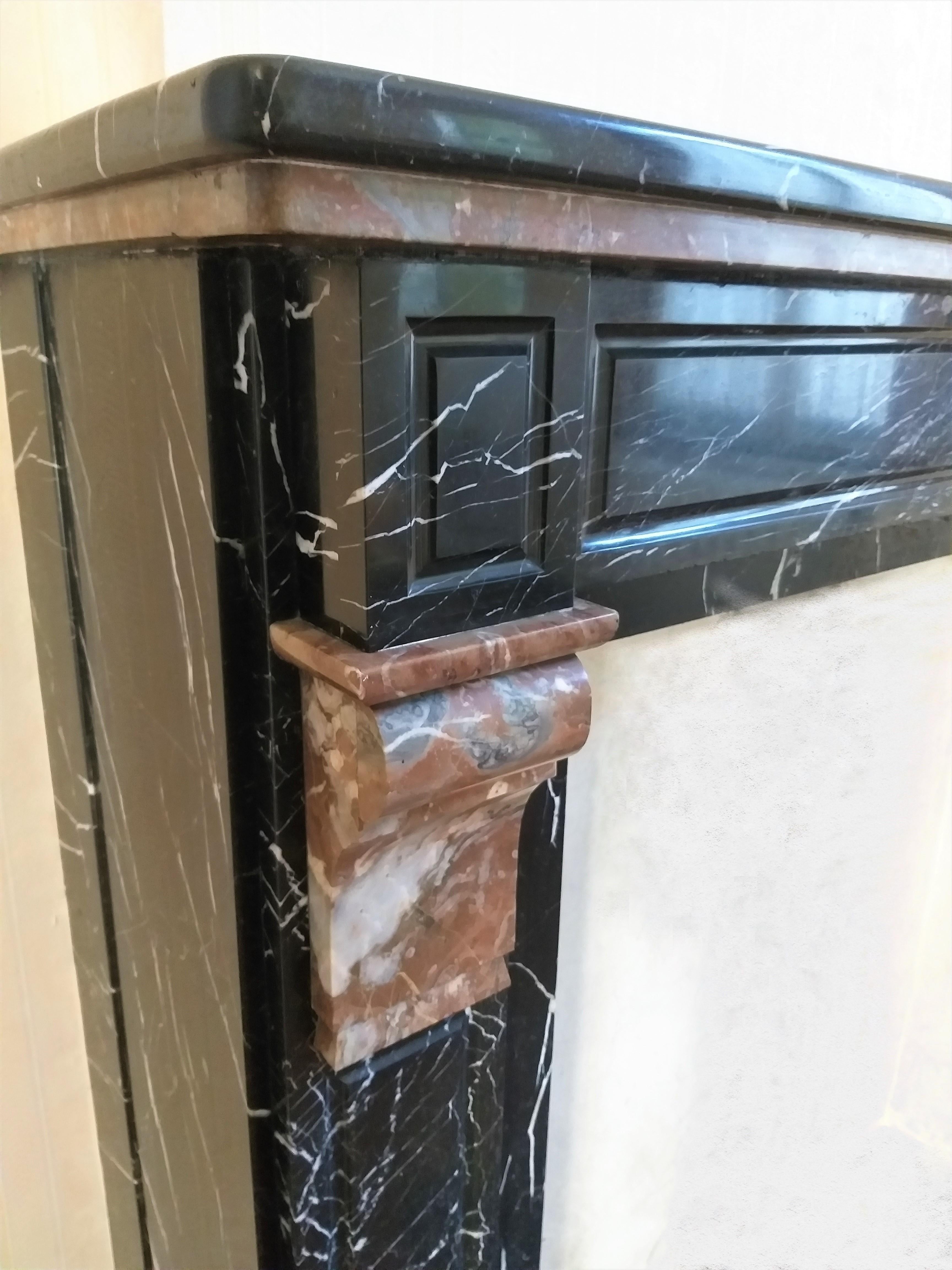 A simple Belgian fireplace from the late 19th century, made out of Nero Marquina and Rouge Royal marbles.
The double moulded shelf rest above a paneled frieze.
The white veins in this black marble brings relief and movement to this fireplace.
All