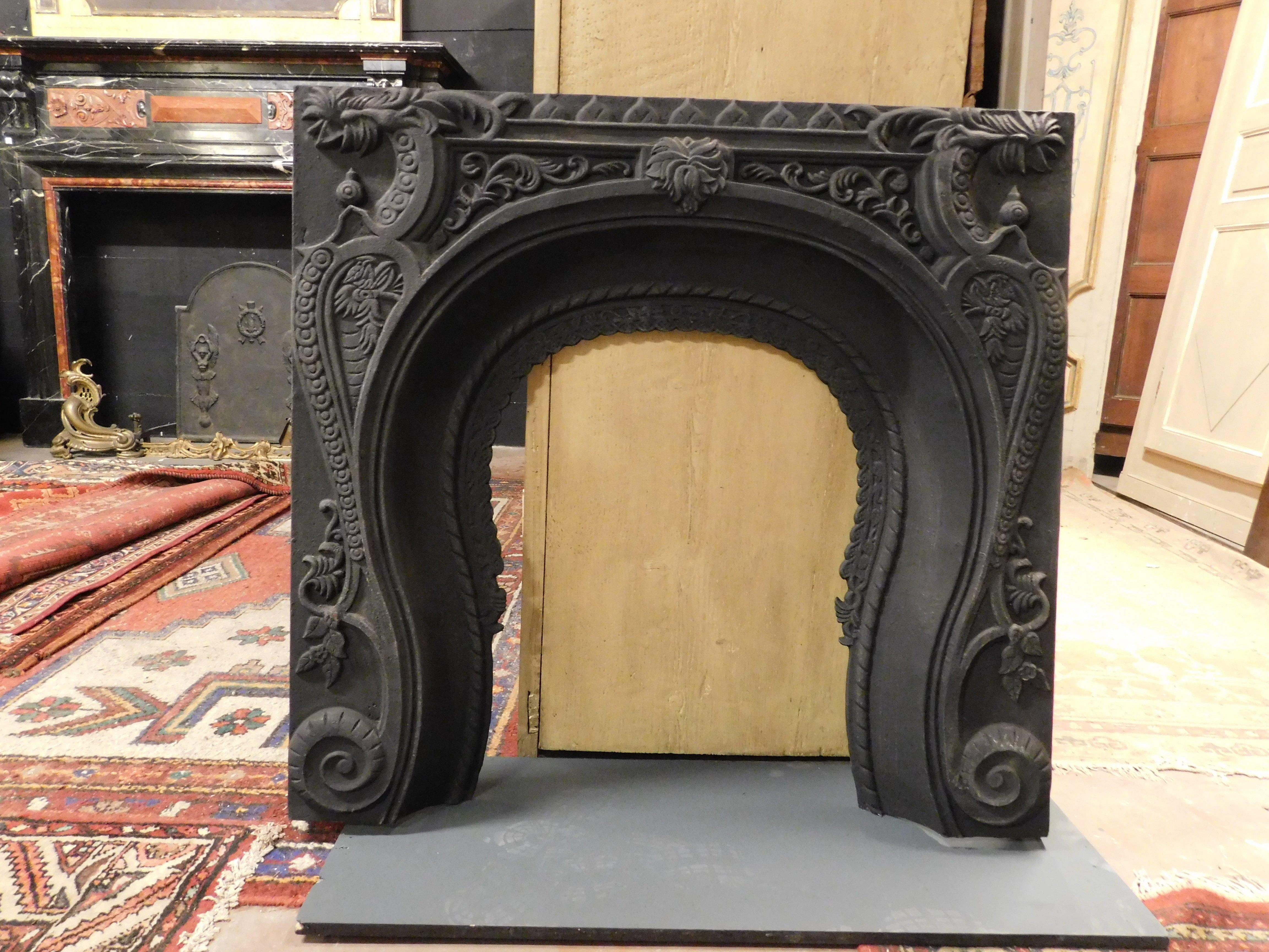 Antique fireplace mantle, carved cast iron stove with very rich floral decorations and rounded mouth, built in the 19th century in Italy and used as a fireplace insert. Given its thickness, it can also be used as a stove pediment, or it could go