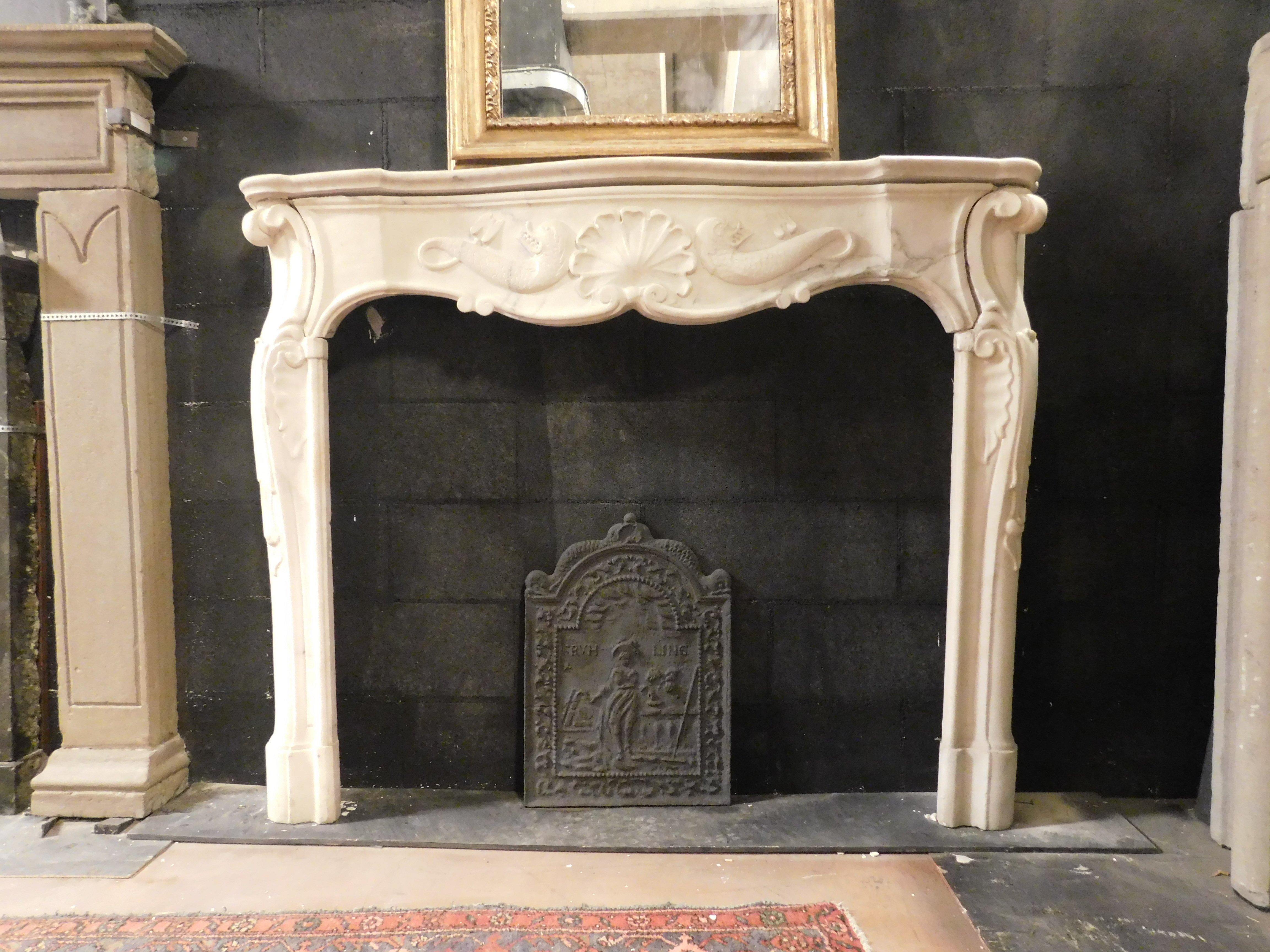 Ancient fireplace mantle in white Carrara marble, hand-sculpted with a central shell and flanked by a pair of tritons symbol of the sea, in fact the fireplace comes from an ancient noble house in Genoa (Italy) and dates back to the 18th century,