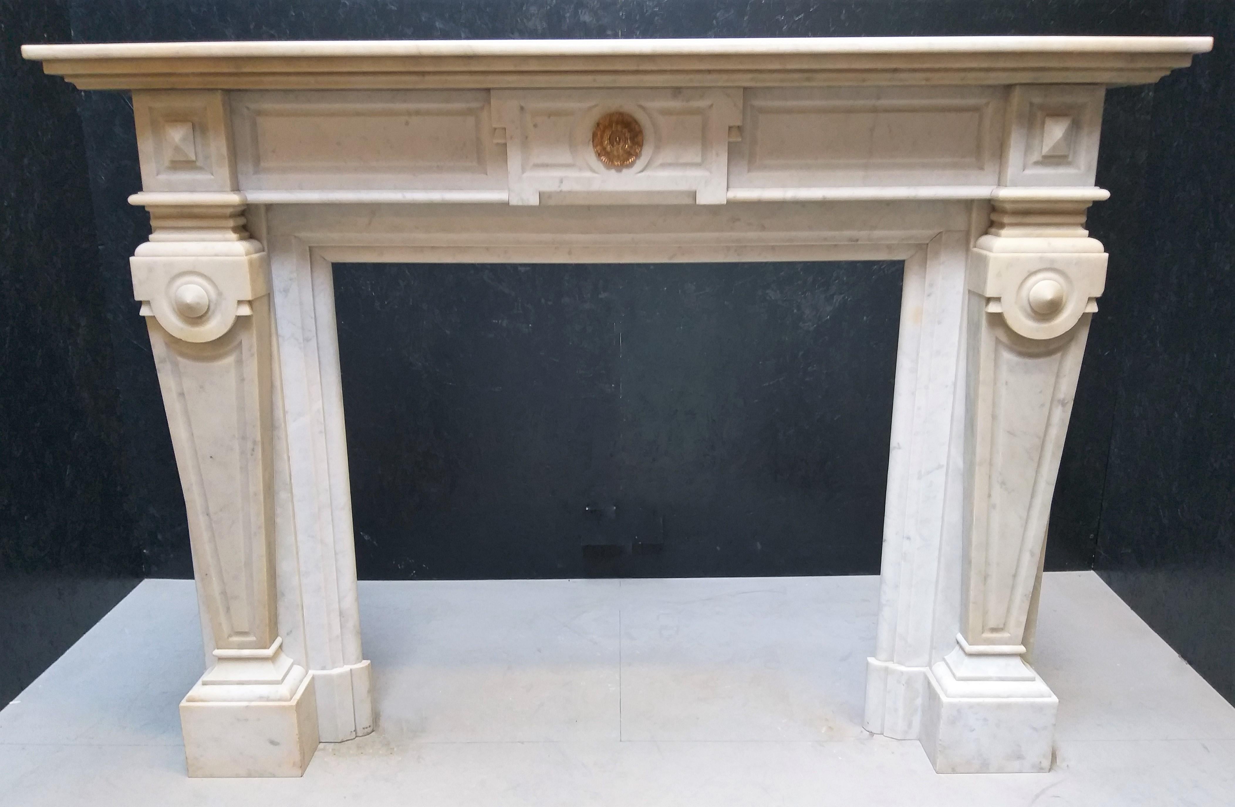 This Napoléon III marble fireplace is made out of demi-statuary Carrara marble, during the late 19th century. It has a little bronze rosette in the center of the frieze and has pilaster-shaped jambs. The Napoléon III style is highly eclectic