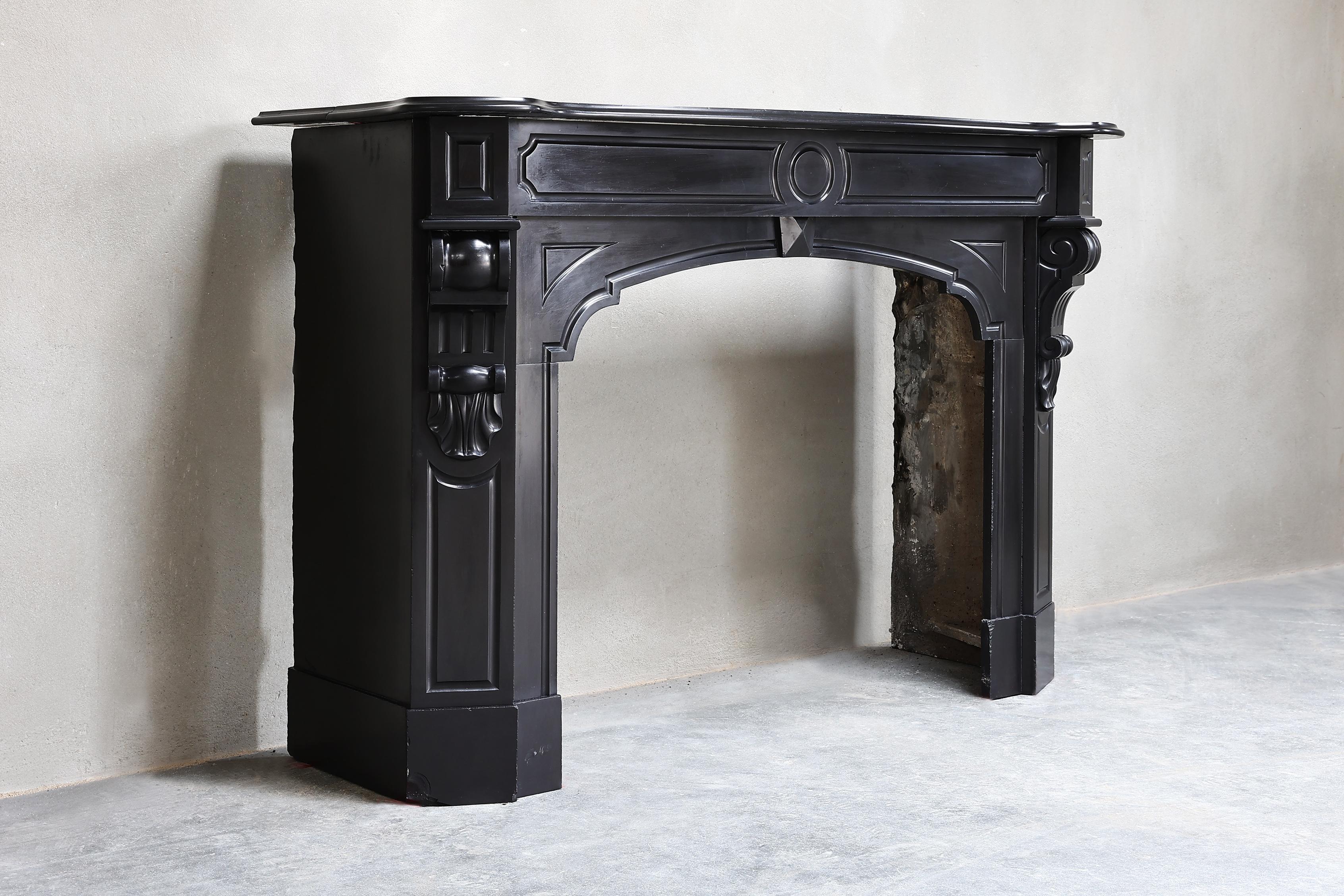 Very chic antique fireplace of Noir de Mazy marble from the 19th century! The elegant fireplace has beautiful ornaments in the front part and on the legs. A beautiful decorative fireplace that looks great in a classic or modern interior!.