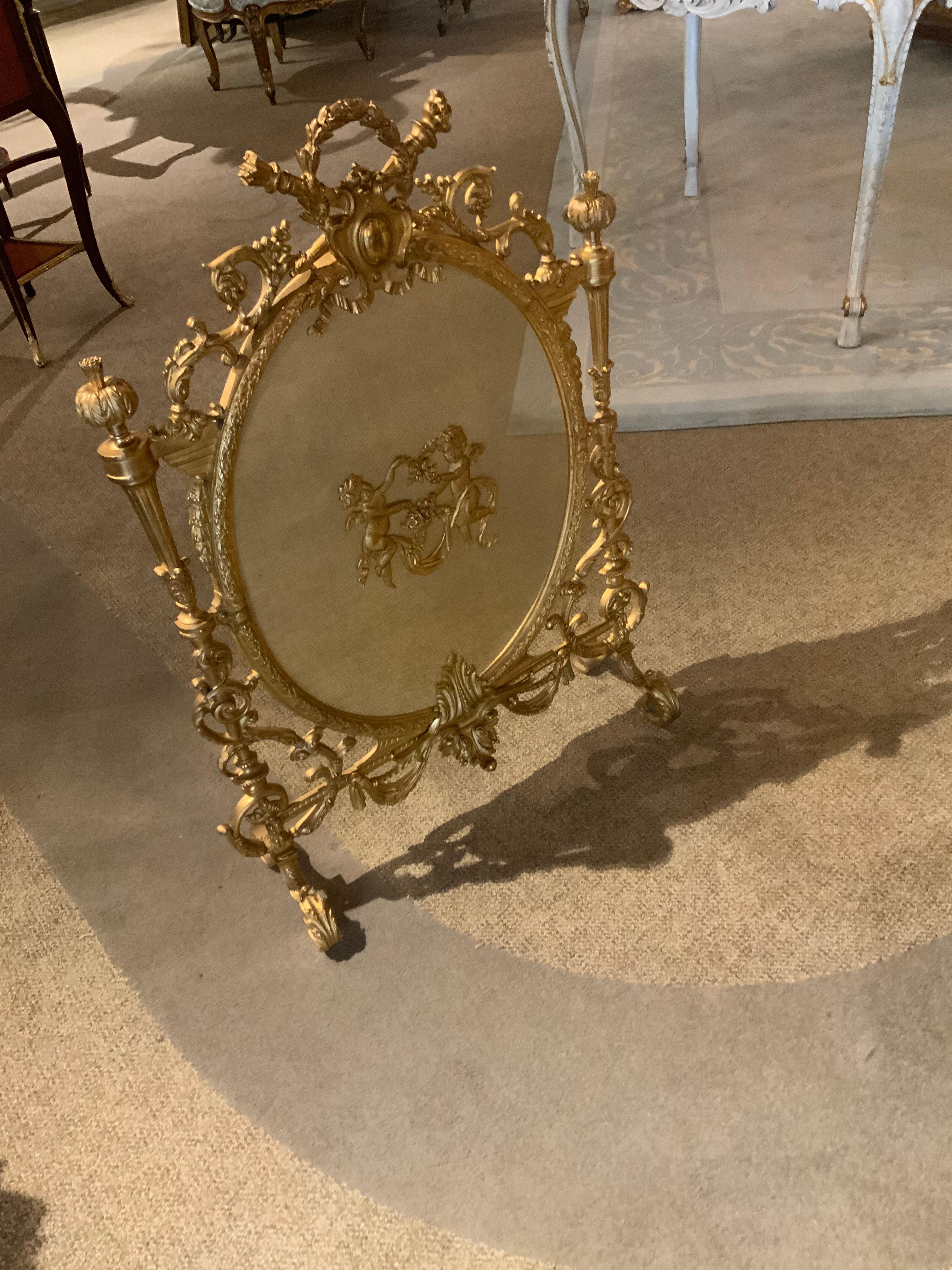 La brillante doratura di questo paravento è della migliore qualità. 
Di bronzo dorato. La forma ovale è aggraziata e
Desiderabile. Al centro ci sono due putti danzanti
Tiene in mano un nastro con disegni floreali e fogliame. La parte superiore
Lo