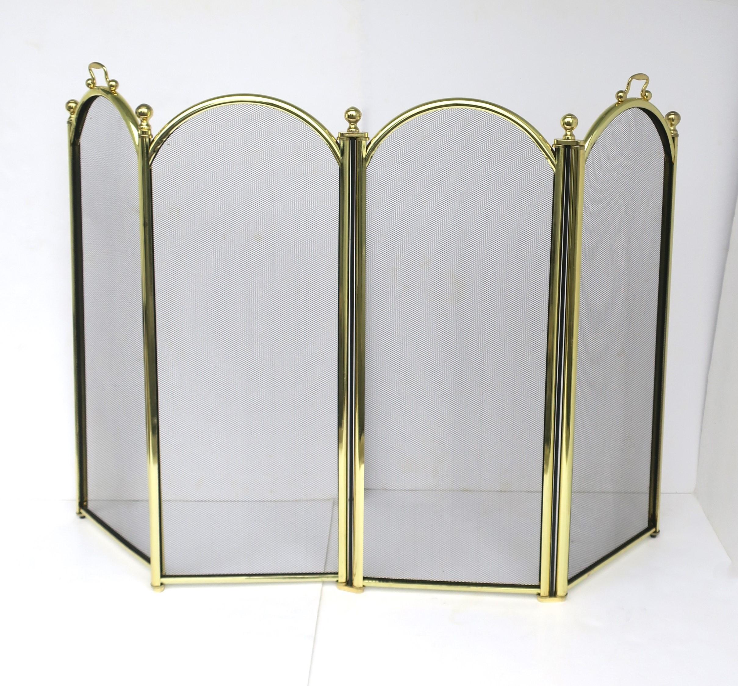 A brass-tone anodized metal fireplace screen with black metal mesh, circa late-20th century. Screen has four panels with black mesh screens, round ball finial details, and handles for easy lifting. Piece folds up nicely as shown. Screen appears to