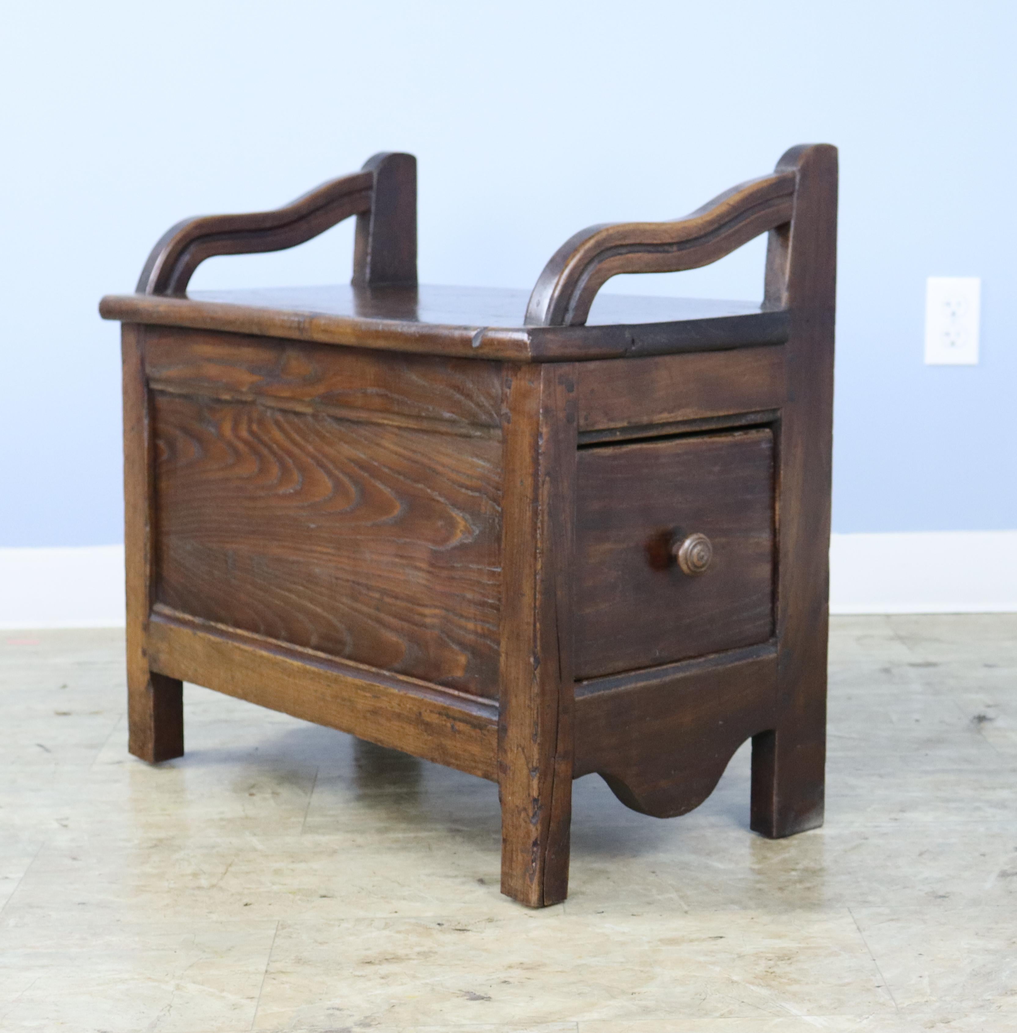 A small fireside seat in warm chestnut with a side drawer that reveals an good storage space.  Attractive curved arms  add a note of charm.  If you are in need of two, we have a similar piece with a side drawer, reference #0623-016A.