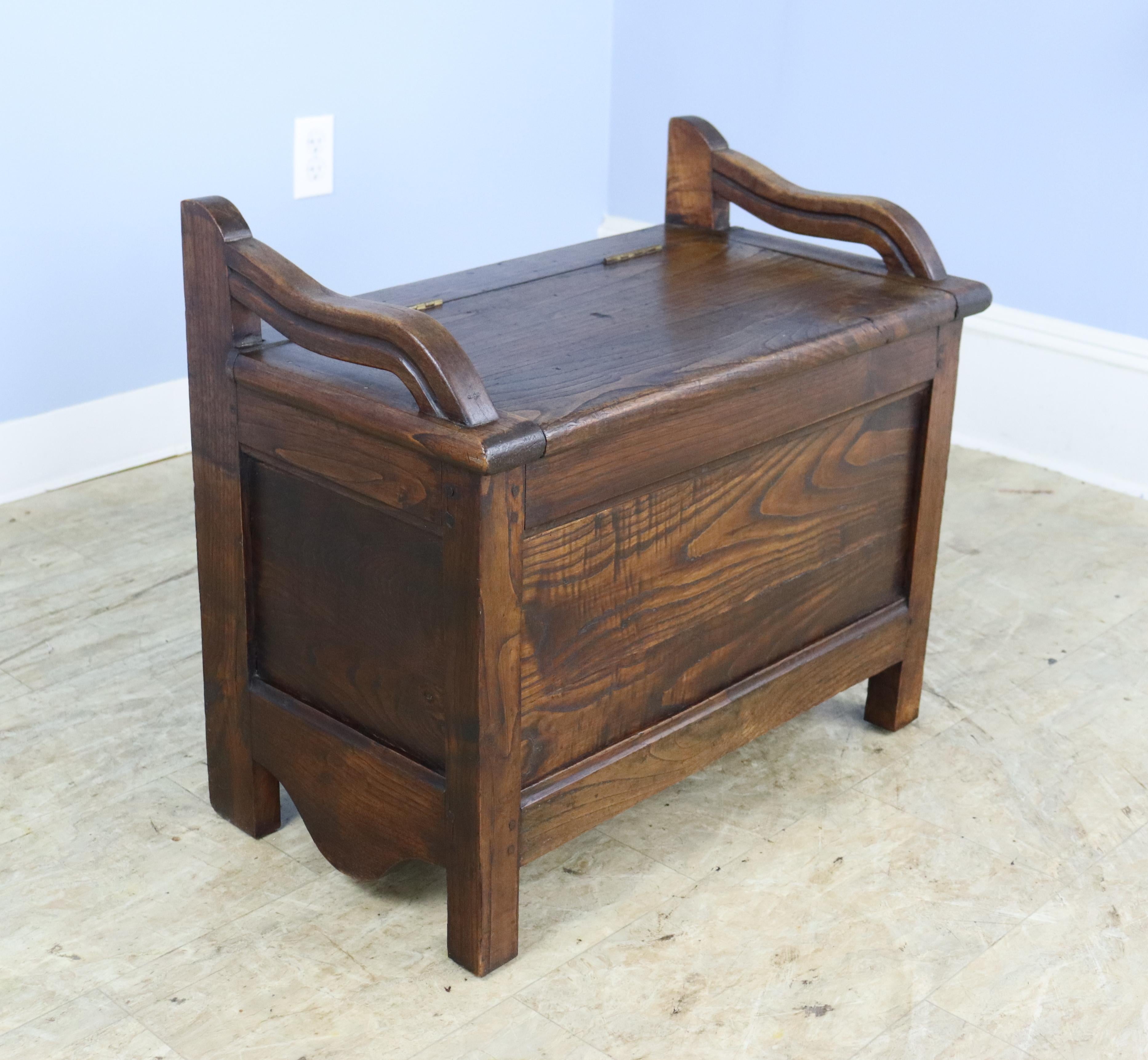 A small fireside seat in warm chestnut with a flip up top that reveals an good storage space.  Attractive curved arms  add a note of charm.  If you are in need of two, we have a similar piece with a side drawer, reference #0623-016B.