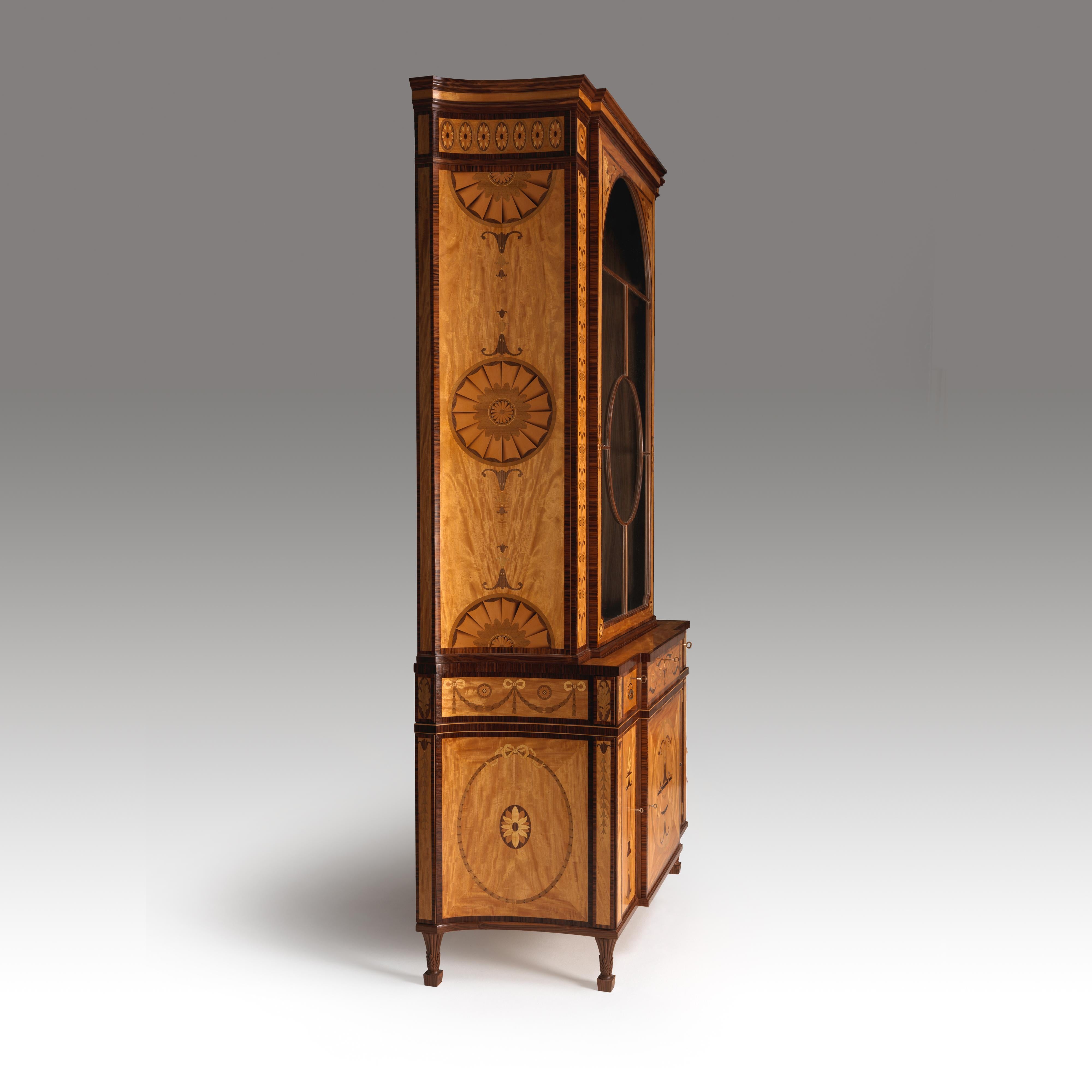 A fine Chippendale design marquetry inlaid satinwood pier cabinet. The base is designed as a cupboard with adjustable interior shelves. There is a central secret drawer, below the glazed top cabinet, with adjustable shelves. The drawers feature hand